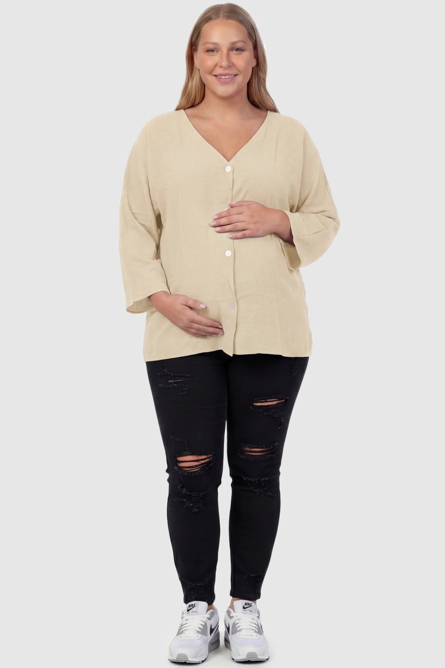 Button Down V-Neck Long Sleeve Maternity Top Button Down V-Neck Long Sleeve Maternity Top in Beige featuring a relaxed drape on a plus size pregnant model, front view.