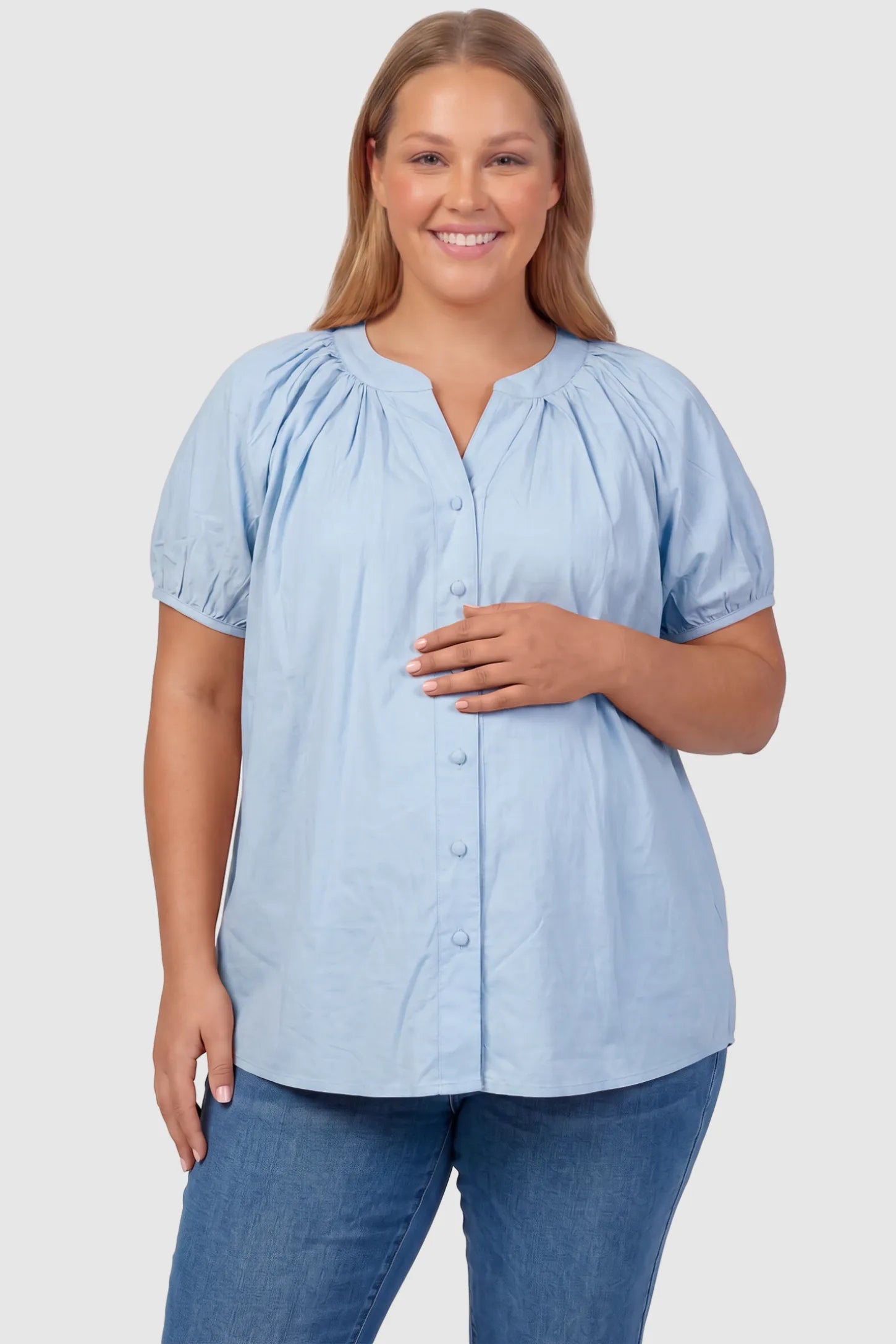 Button Front Short Sleeve Maternity Blouse Button Front Short Sleeve Maternity Blouse in Blue featuring gathered fabric and a button-up neck on a plus size pregnant model, front view.