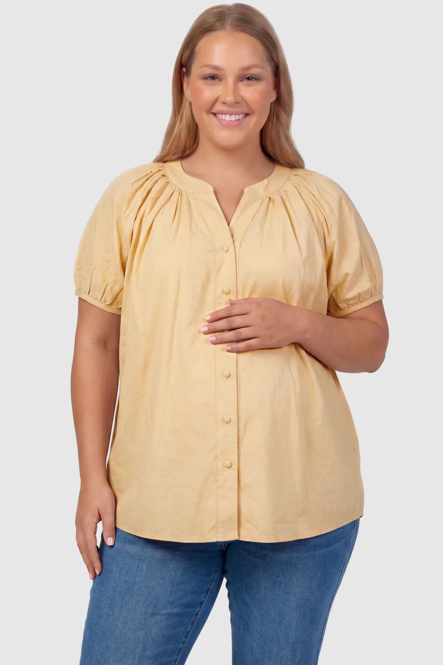 Button Front Short Sleeve Maternity Blouse Button Front Short Sleeve Maternity Blouse in Yellow featuring gathered fabric and a button-up neck on a plus size pregnant model, front view.
