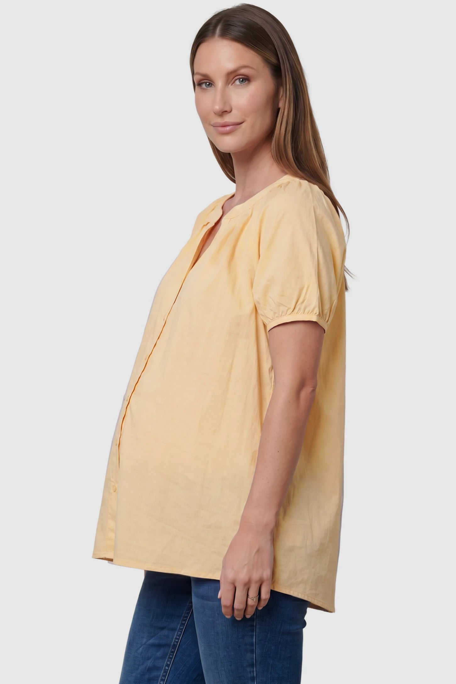 Button Front Short Sleeve Maternity Blouse Button Front Short Sleeve Maternity Blouse in Yellow featuring gathered fabric and a button-up neck on a pregnant model, side view.