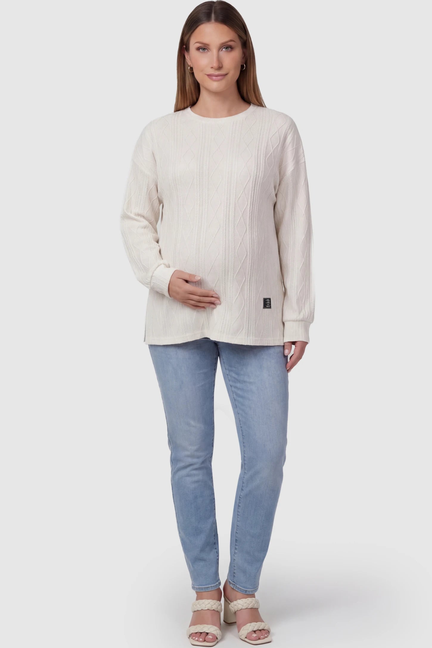 Cable Knit Long Sleeve Maternity Sweater in apricot featuring a breathable textured weave on a pregnant model posing front.