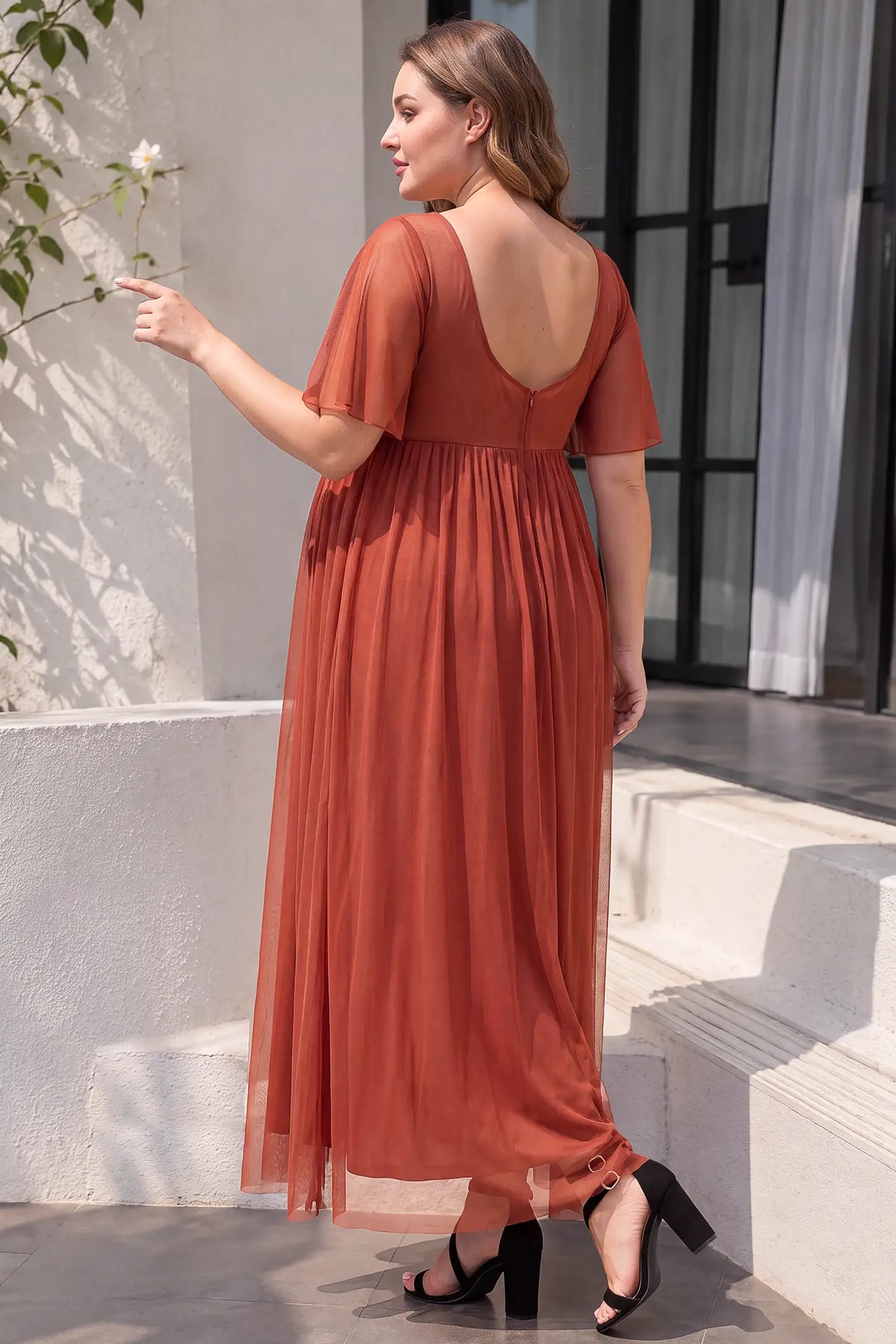 Chiffon Flutter Sleeve V-Neck Maternity Maxi Dress Chiffon Flutter Sleeve V-Neck Maternity Maxi Dress in Rust highlighting the back detail on a pregnant model, lifestyle back view.