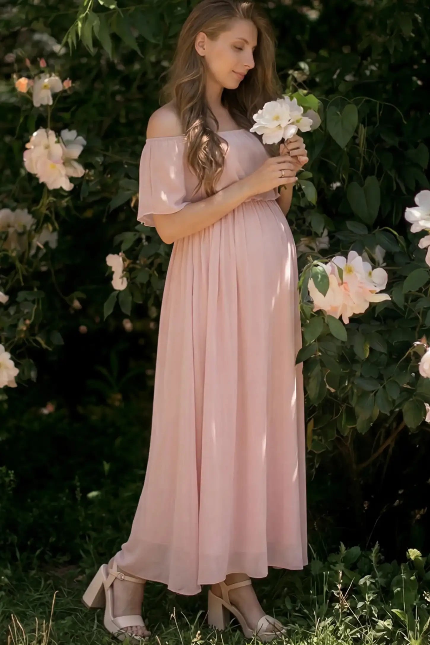 Chiffon Off-Shoulder Maternity Maxi Dress in Pink featuring a Floor-length on a pregnant woman showing side.