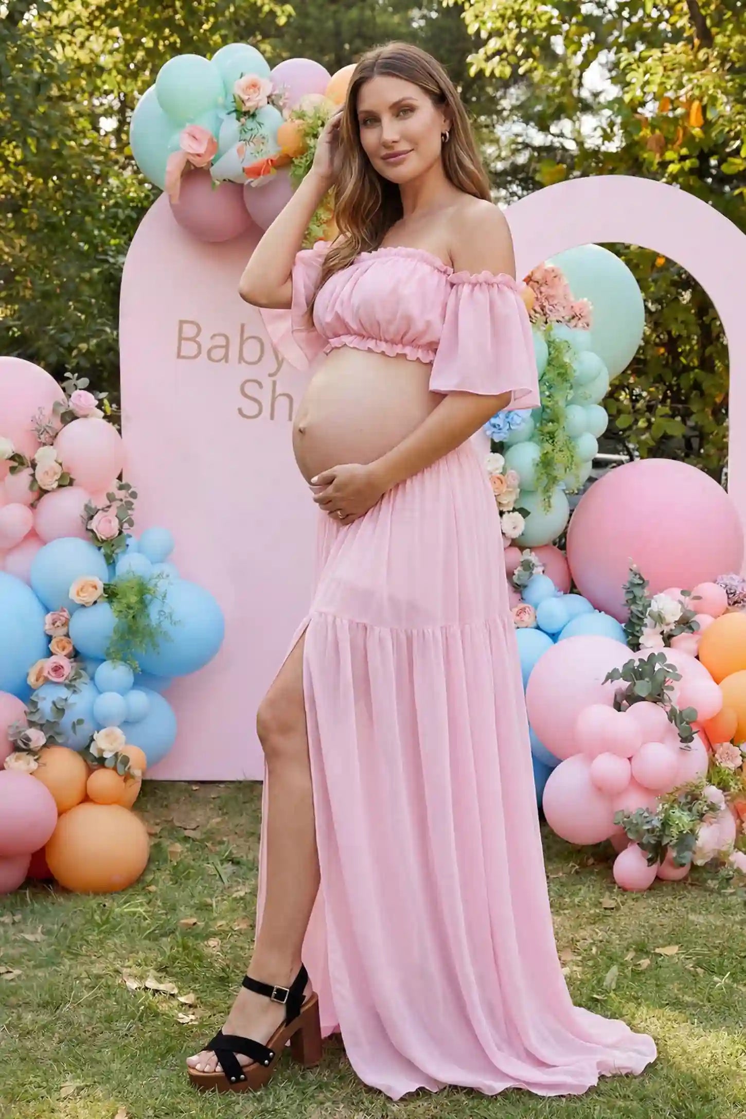 Chiffon Ruffle Off-Shoulder Two-Piece Maxi Maternity Dress Chiffon Ruffle Off-Shoulder Two-Piece Maxi Maternity Dress in Pink featuring a flowy thigh-high slit skirt on a pregnant model, side view.
