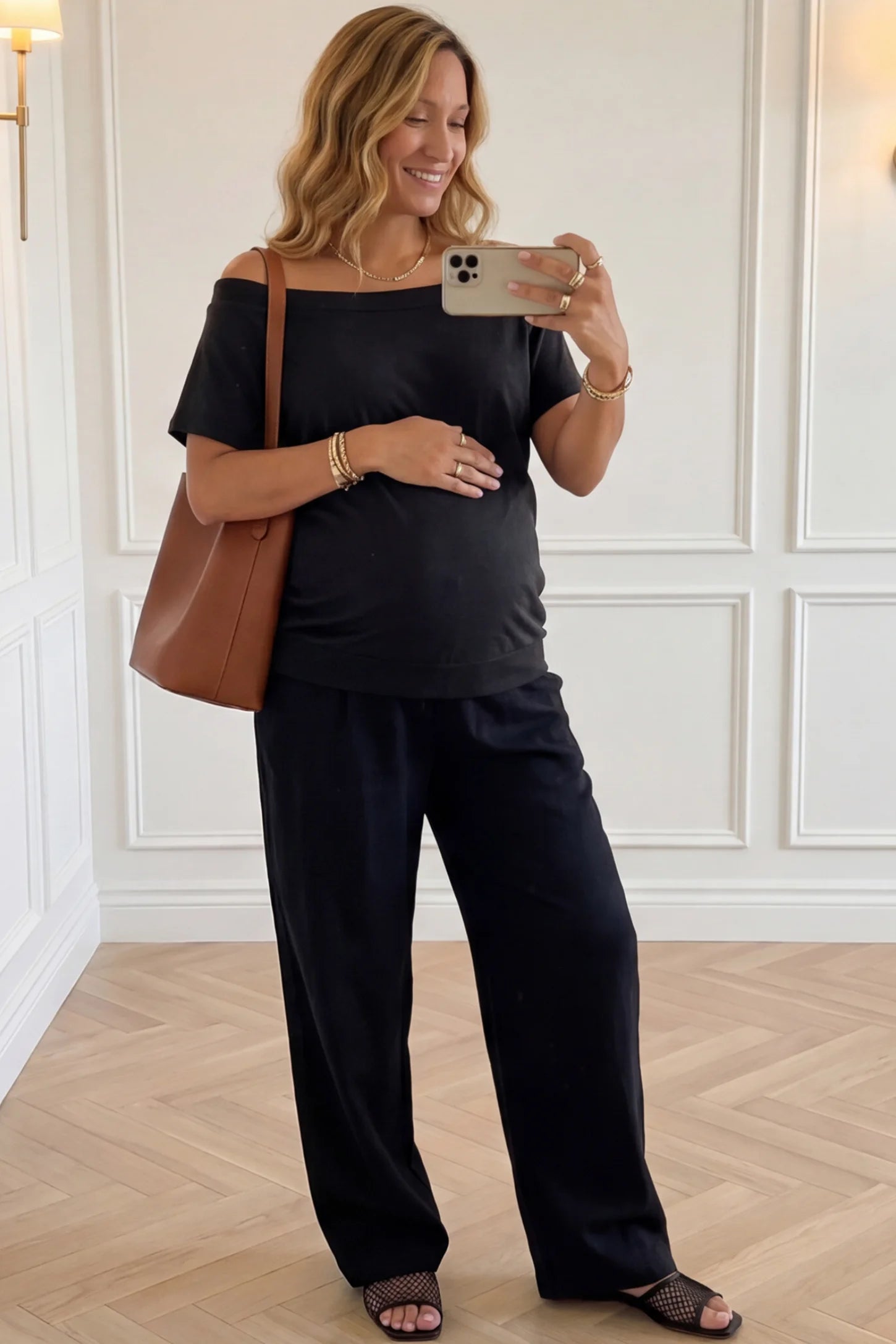 Convertible Neck Short Sleeve Maternity Top Convertible Neck Short Sleeve Maternity Top in black featuring an adjustable neckline and a comfortable banded hem paired with black pants worn by a pregnant woman in an indoor setting front view.