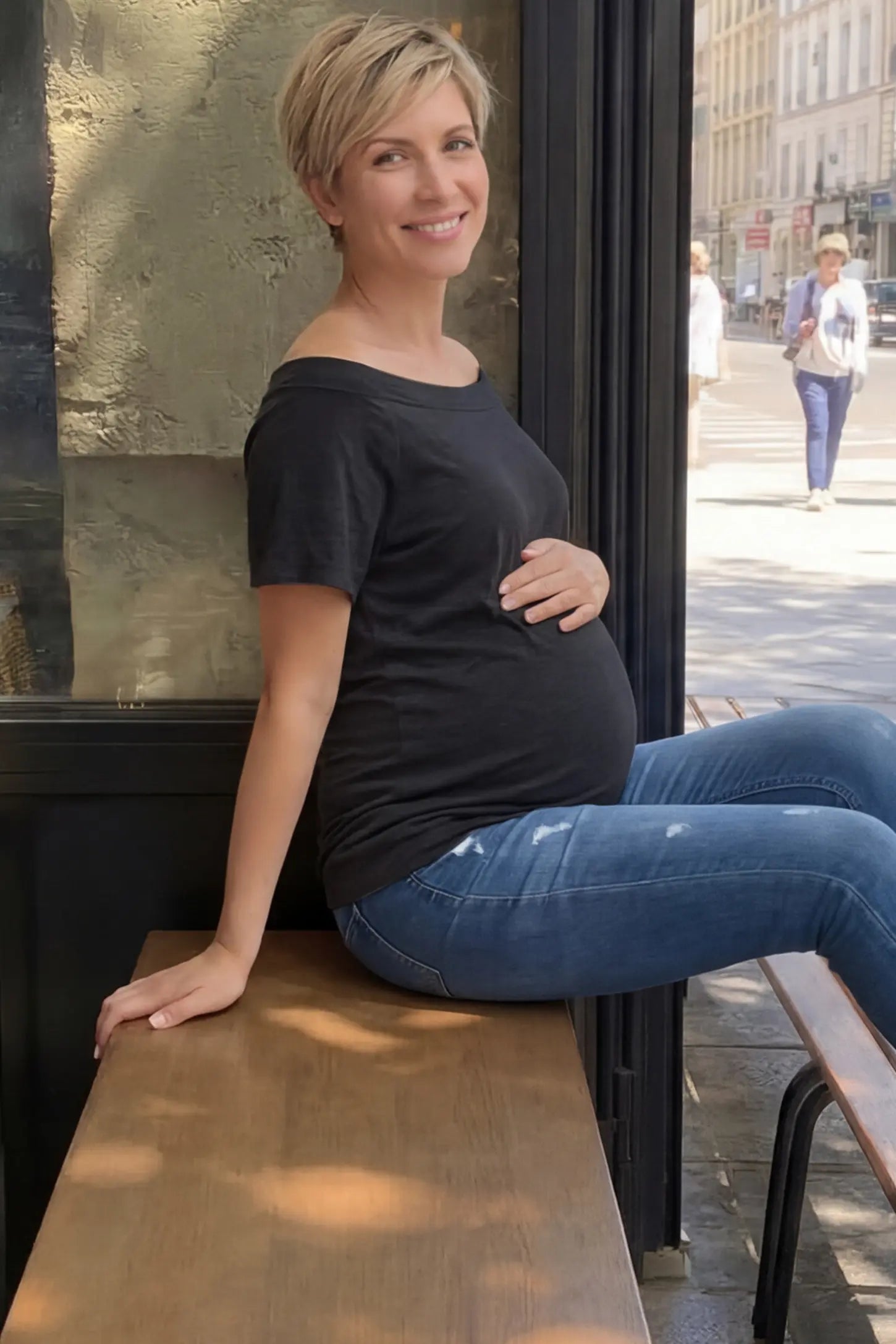 Convertible Neck Short Sleeve Maternity Top Convertible Neck Short Sleeve Maternity Top in dark gray featuring an adjustable neckline and a comfortable banded hem paired with blue jeans worn by a pregnant woman in an outdoor setting side view.