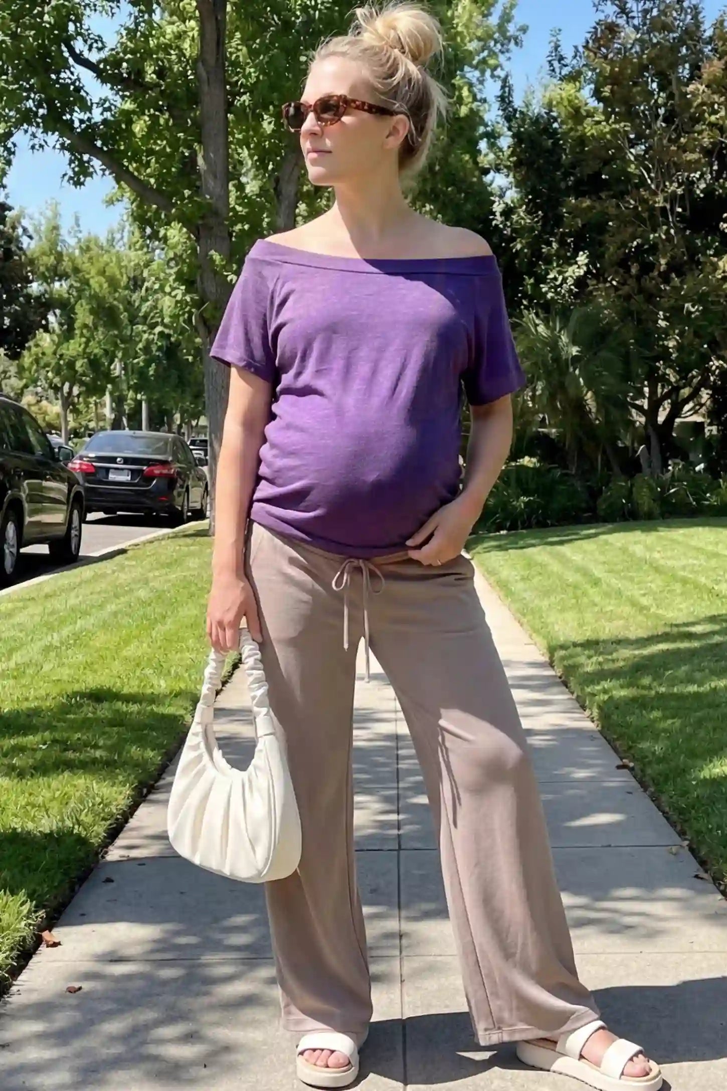 Convertible Neck Short Sleeve Maternity Top Convertible Neck Short Sleeve Maternity Top in purple featuring an adjustable neckline and a comfortable banded hem paired with pants worn by a pregnant woman in an outdoor setting front view.