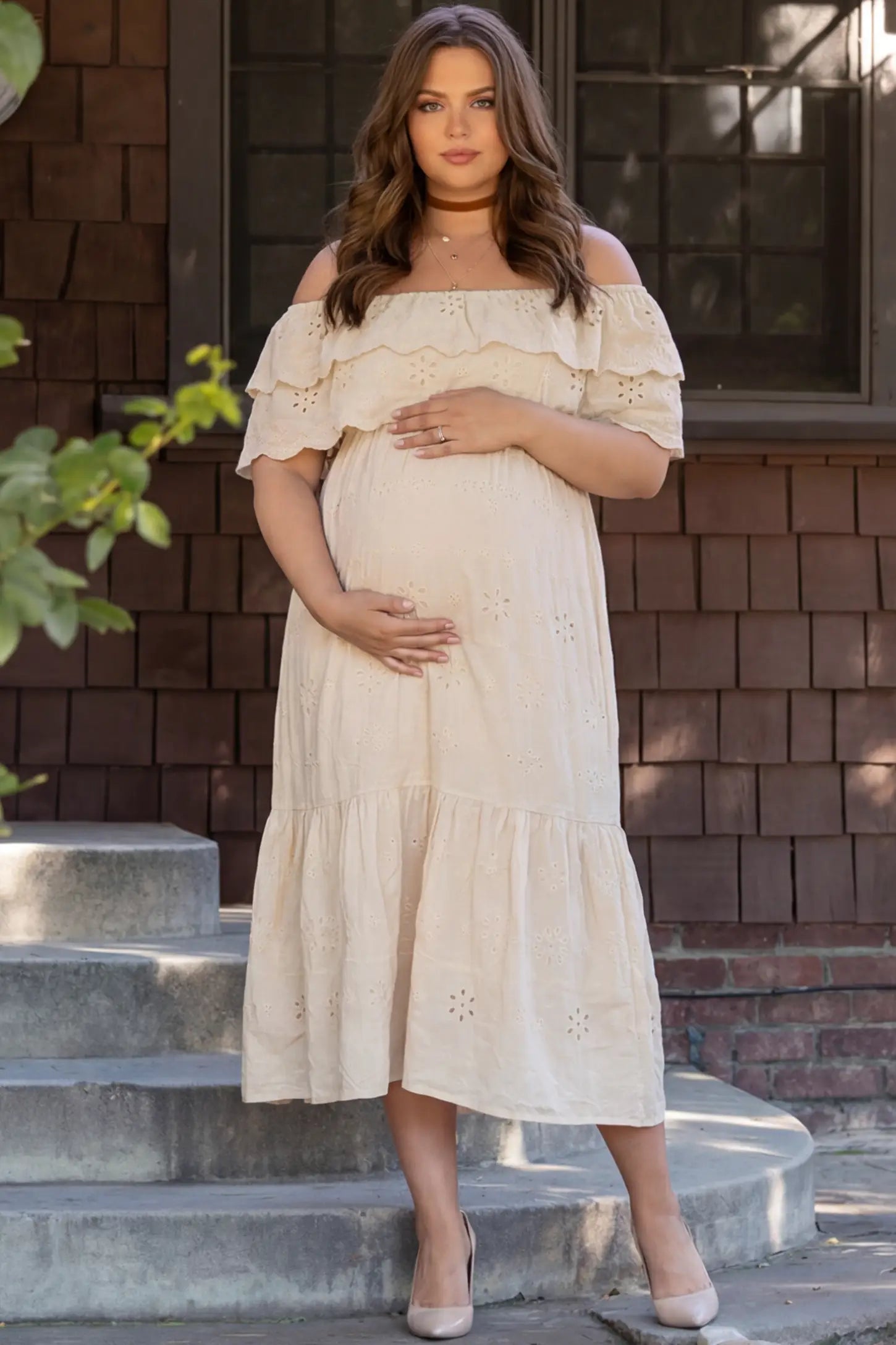 Convertible Neckline Tiered Maternity Midi Dress Convertible Neckline Tiered Maternity Midi Dress in Yellow featuring eyelet embroidery on a pregnant model in outdoor setting, front view.