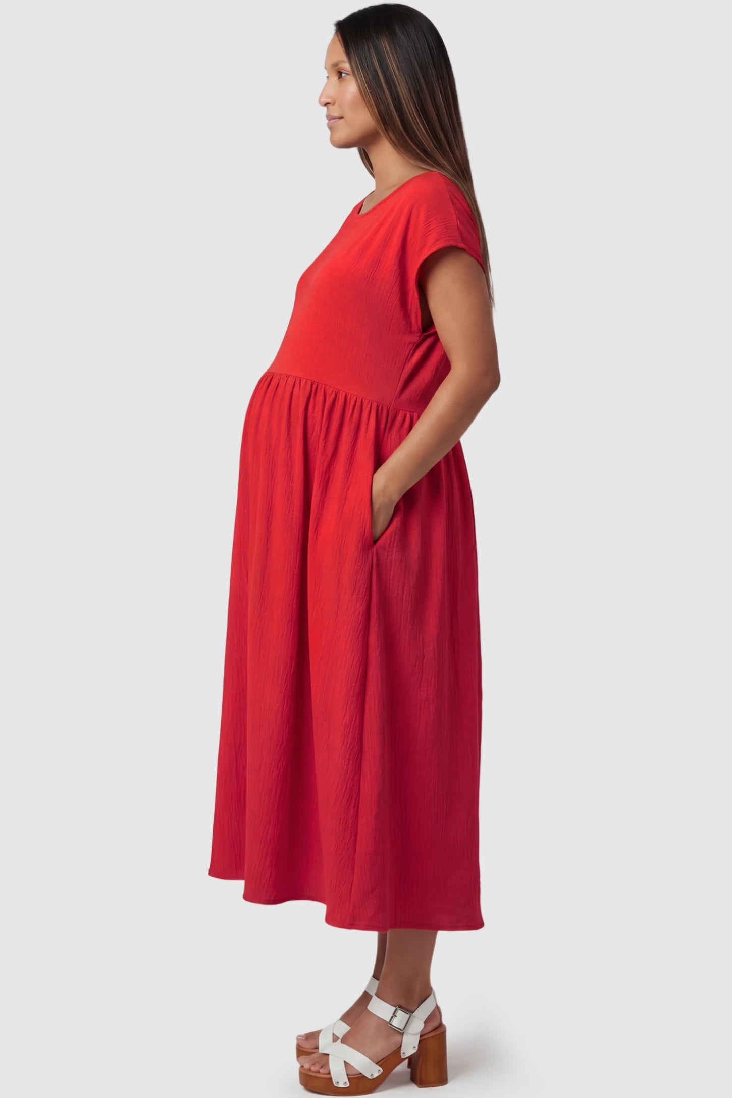 Crew Neck Short Sleeve Maternity Midi Dress Crew Neck Short Sleeve Maternity Midi Dress in Red featuring a flowy shift silhouette on a pregnant model, side view.