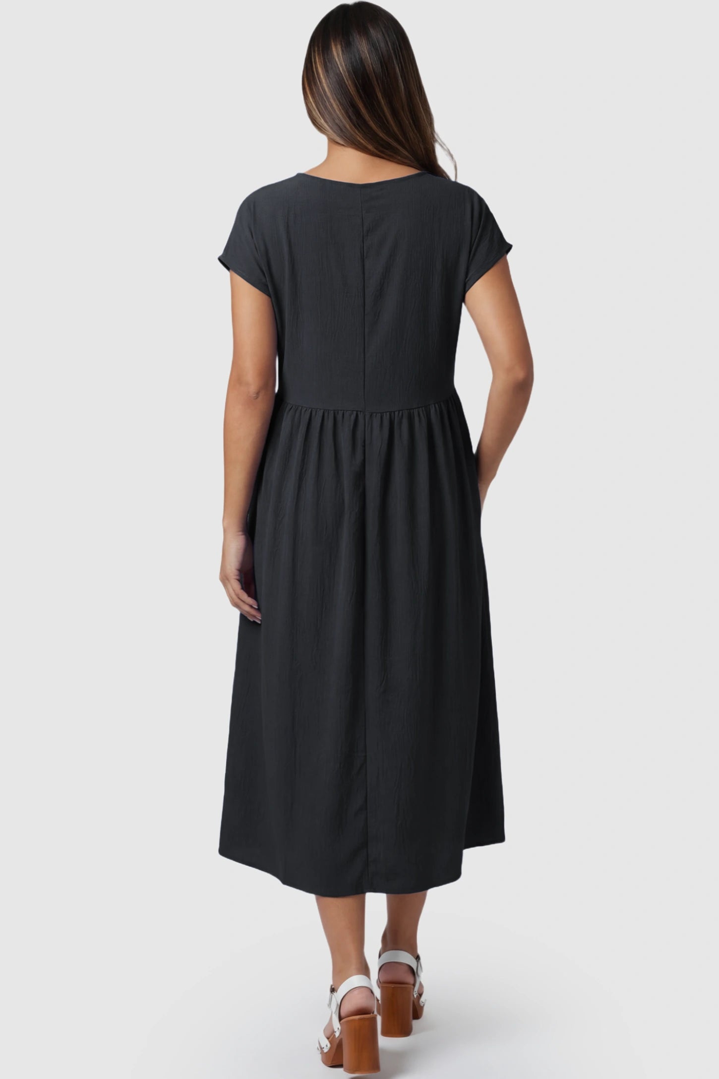 Crew Neck Short Sleeve Maternity Midi Dress Crew Neck Short Sleeve Maternity Midi Dress in Black featuring a flowy shift silhouette on a pregnant model, back view.