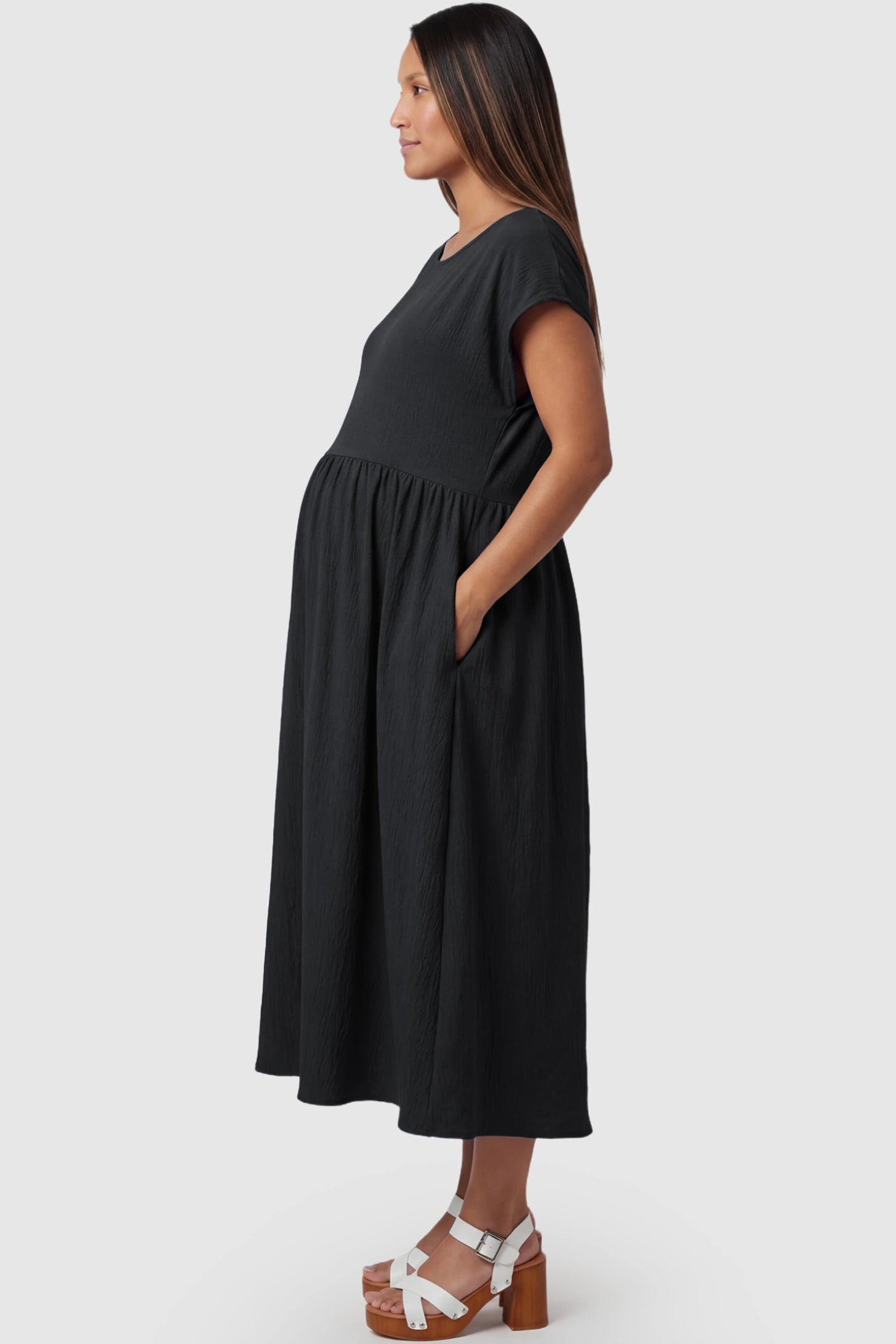 Crew Neck Short Sleeve Maternity Midi Dress Crew Neck Short Sleeve Maternity Midi Dress in Black featuring a flowy shift silhouette on a pregnant model, side view.