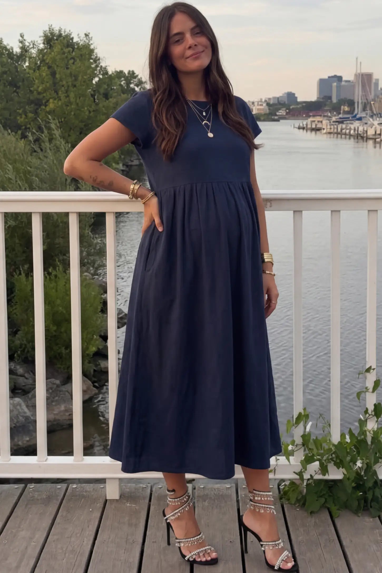 Crew Neck Short Sleeve Maternity Midi Dress Crew Neck Short Sleeve Maternity Midi Dress in Navy blue featuring a flowy shift silhouette on a pregnant woman, front view.