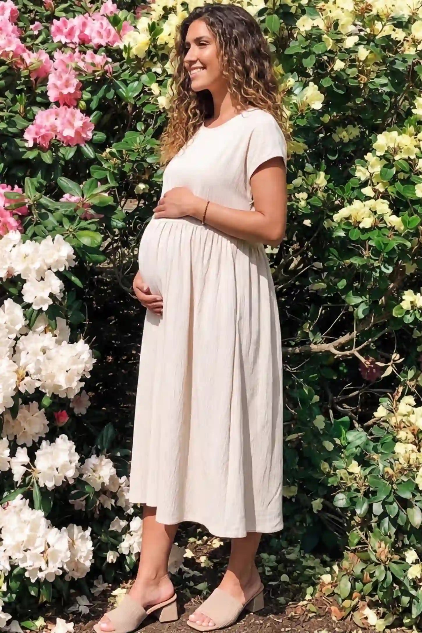 Crew Neck Short Sleeve Maternity Midi Dress Crew Neck Short Sleeve Maternity Midi Dress in White featuring a flowy shift silhouette on a pregnant woman, side view.