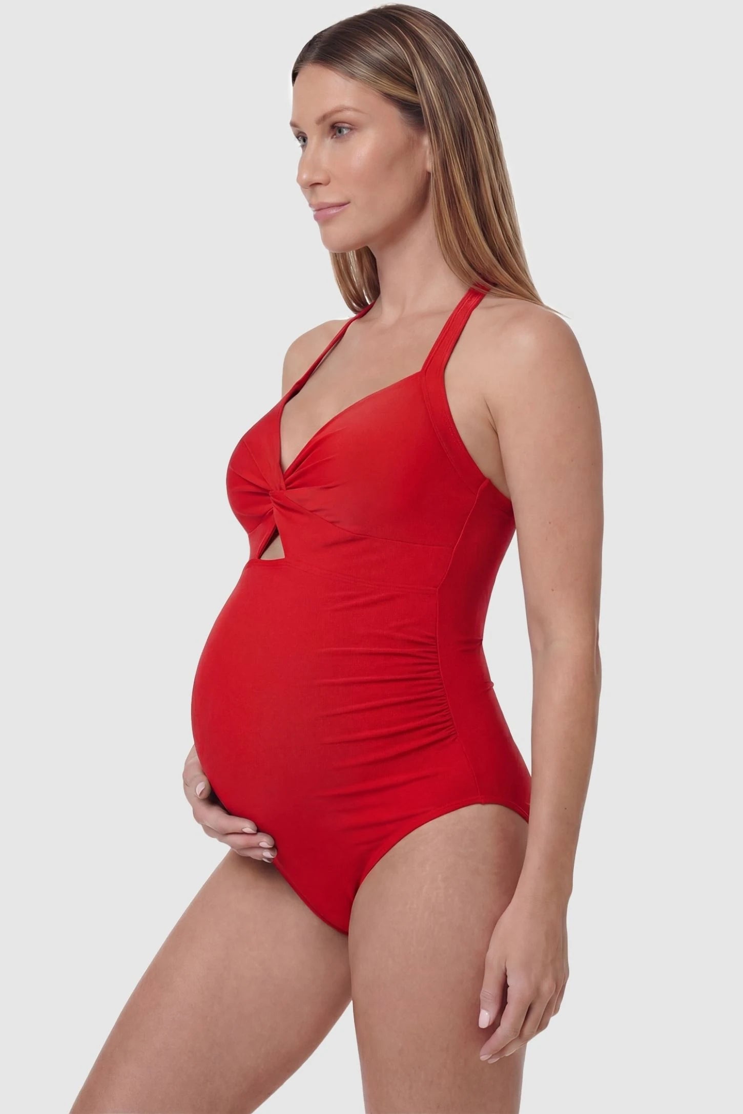Criss-Cross Back Twist-Front Maternity One-Piece Criss-Cross Back Twist-Front Maternity One-Piece in Red featuring flattering side ruching on a pregnant model, side view.