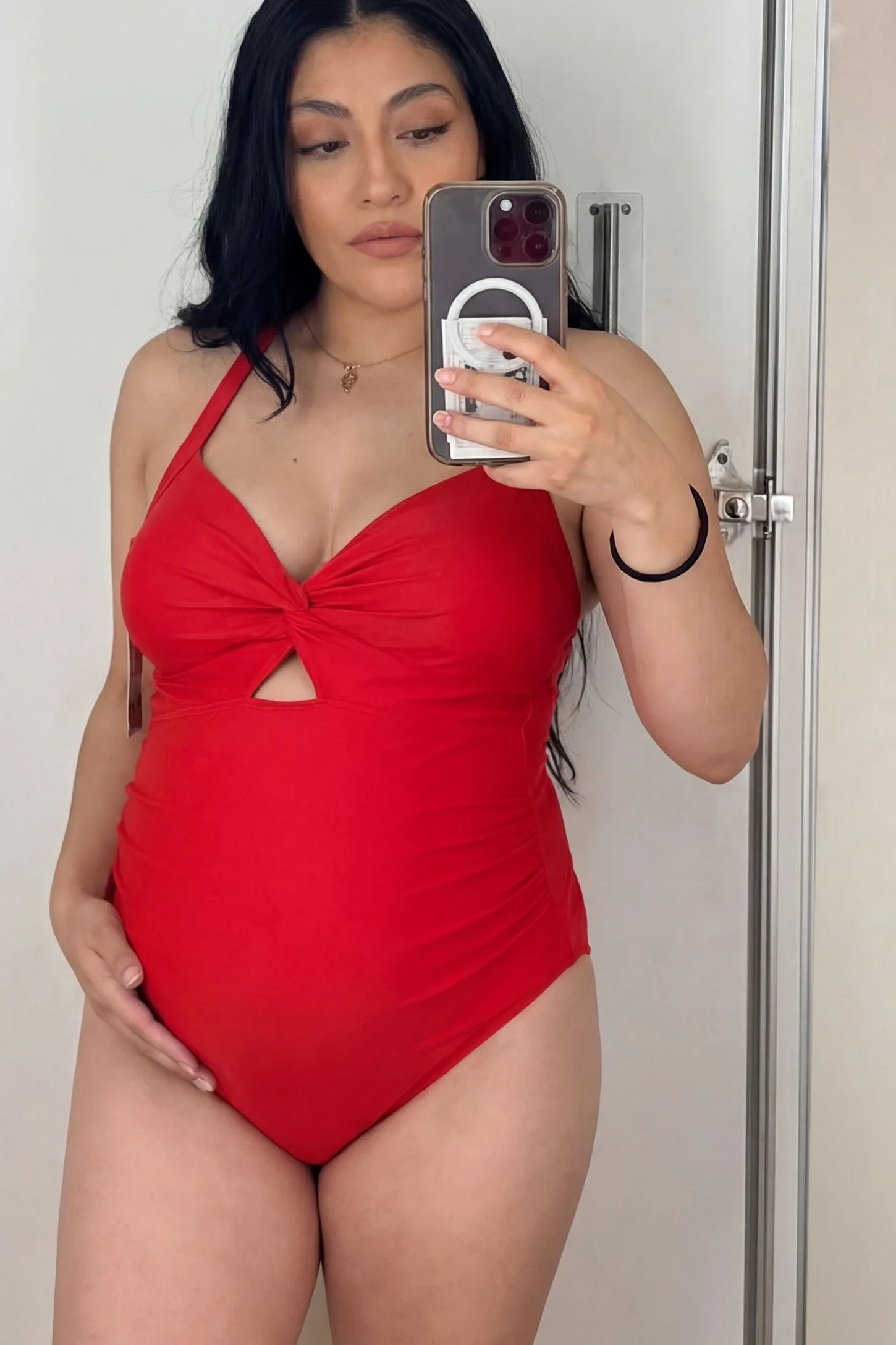 Criss-Cross Back Twist-Front Maternity One-Piece Criss-Cross Back Twist-Front Maternity One-Piece in Red featuring high-stretch fabric on a pregnant model in a mirror selfie.