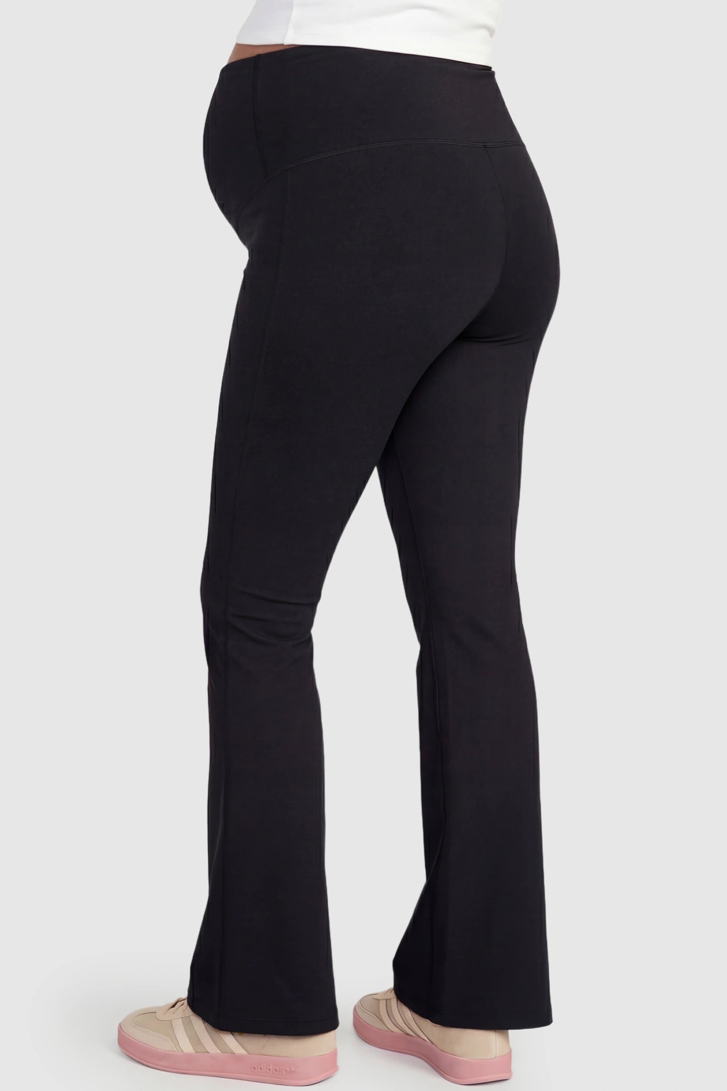 Crossover Waistline Flared Maternity Pants Crossover Waistline Flared Maternity Pants in Black featuring flared leg on a pregnant model, back view.