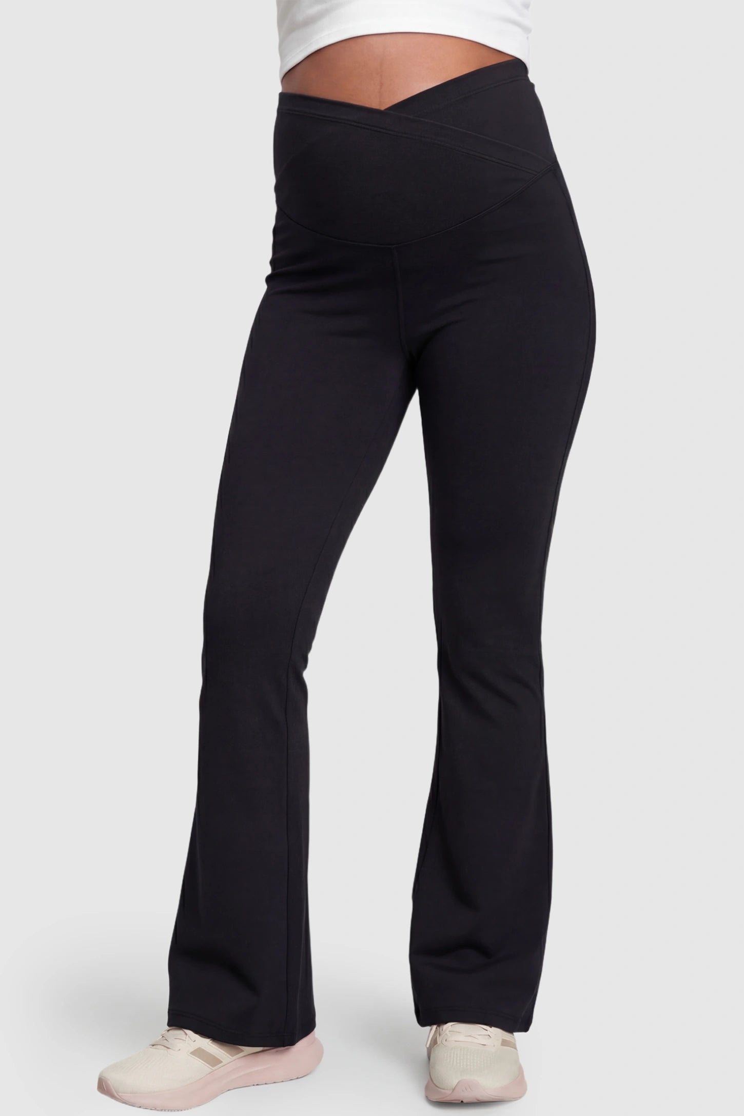 Crossover Waistline Flared Maternity Pants in Black featuring a V-shaped band on a pregnant model, front view.