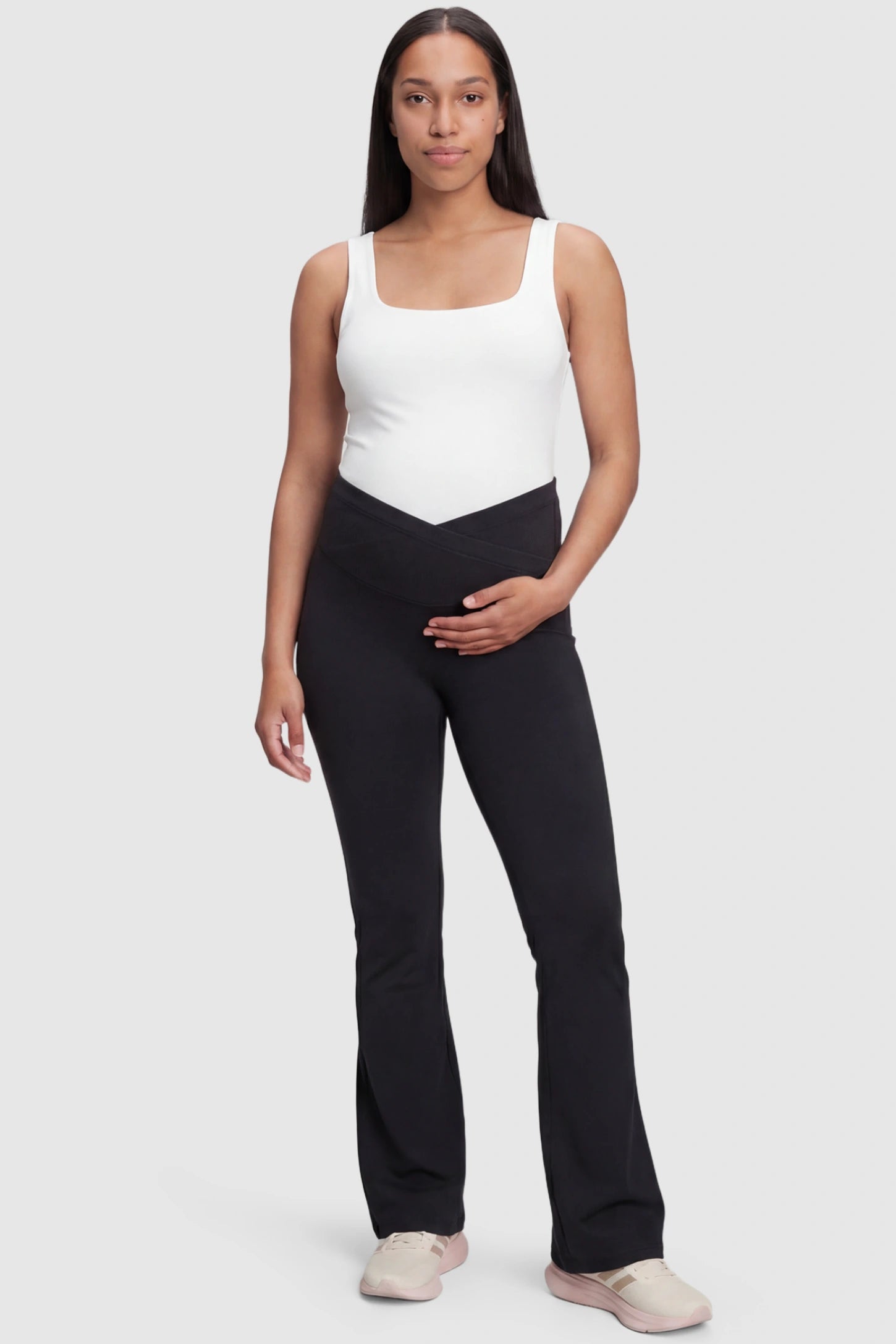 Crossover Waistline Flared Maternity Pants in Black featuring a V-shaped band on a pregnant model, full body view.
