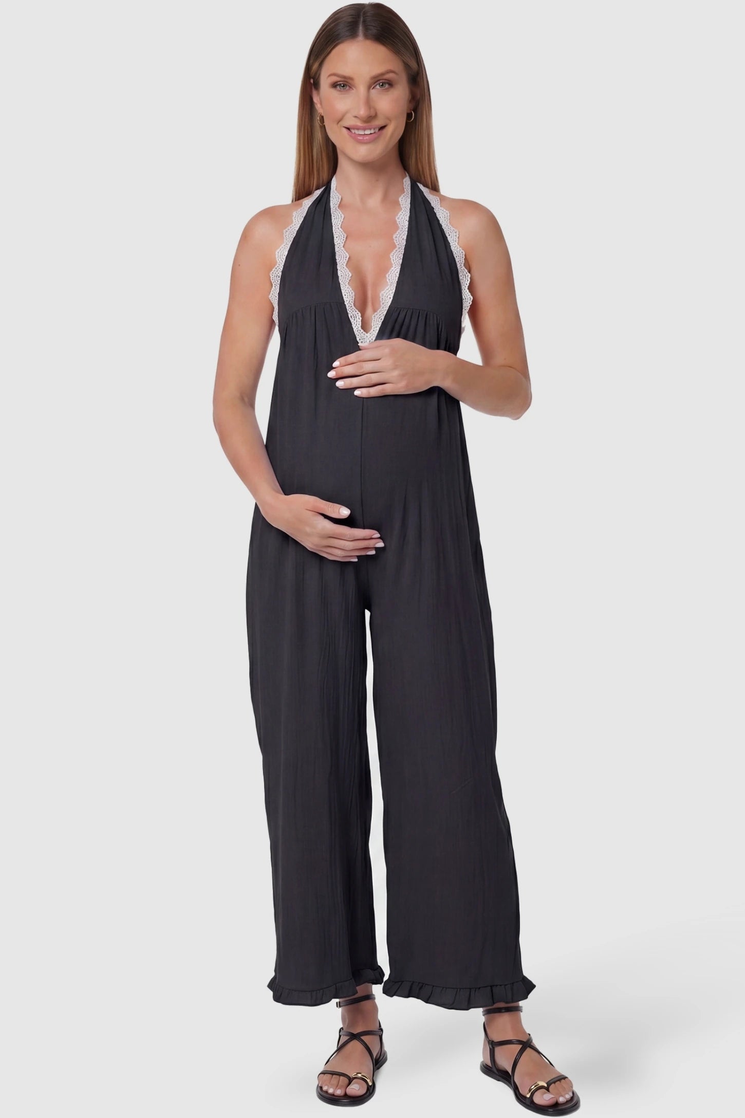 Deep V-Neck Lace Trim Wide Leg Maternity Jumpsuit Deep V-Neck Lace Trim Wide Leg Maternity Jumpsuit in Black featuring a deep V-neckline with delicate lace trim on a pregnant model, front view.