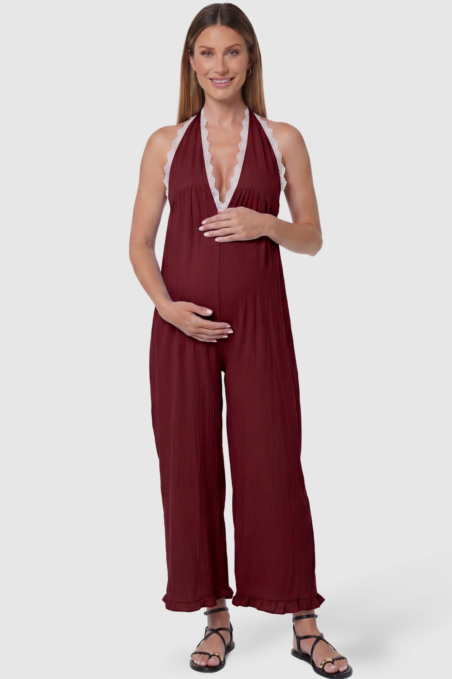 Deep V-Neck Lace Trim Wide Leg Maternity Jumpsuit Deep V-Neck Lace Trim Wide Leg Maternity Jumpsuit in Burgundy featuring a deep V-neckline with delicate lace trim on a pregnant model, front view.
