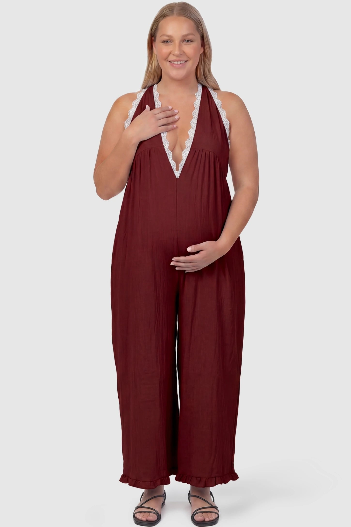 Deep V-Neck Lace Trim Wide Leg Maternity Jumpsuit Deep V-Neck Lace Trim Wide Leg Maternity Jumpsuit in Burgundy featuring a flattering wide leg cut with lace trim neckline on a plus-size model, front view.