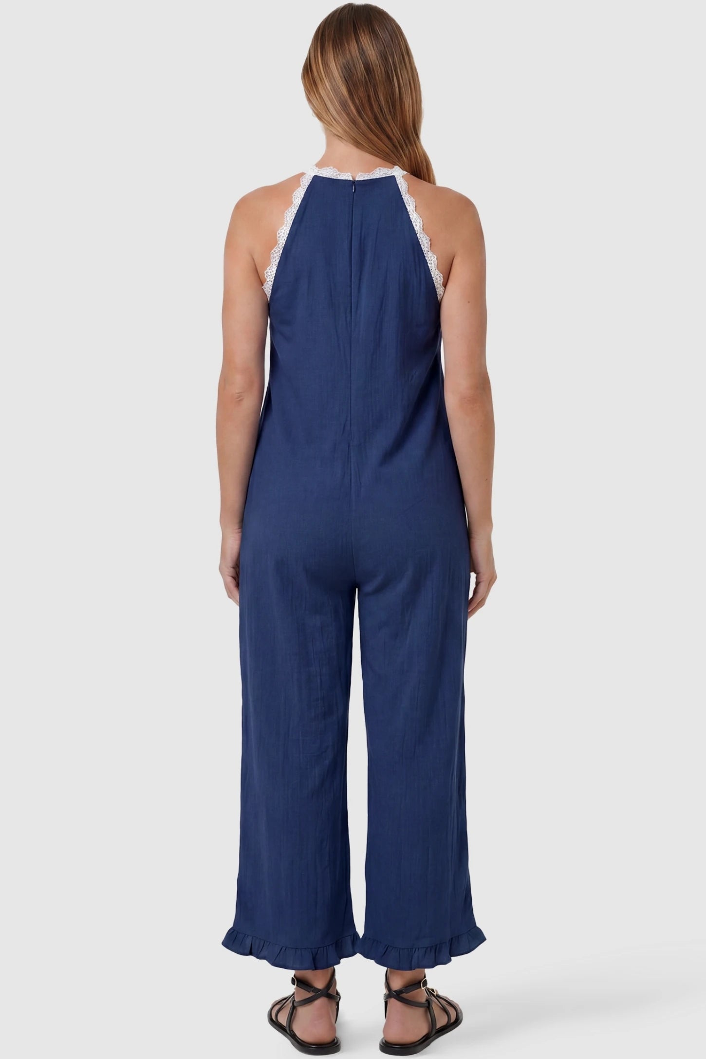 Deep V-Neck Lace Trim Wide Leg Maternity Jumpsuit Deep V-Neck Lace Trim Wide Leg Maternity Jumpsuit in Navy Blue featuring an open back design with lace trim finish on a pregnant model, back view.