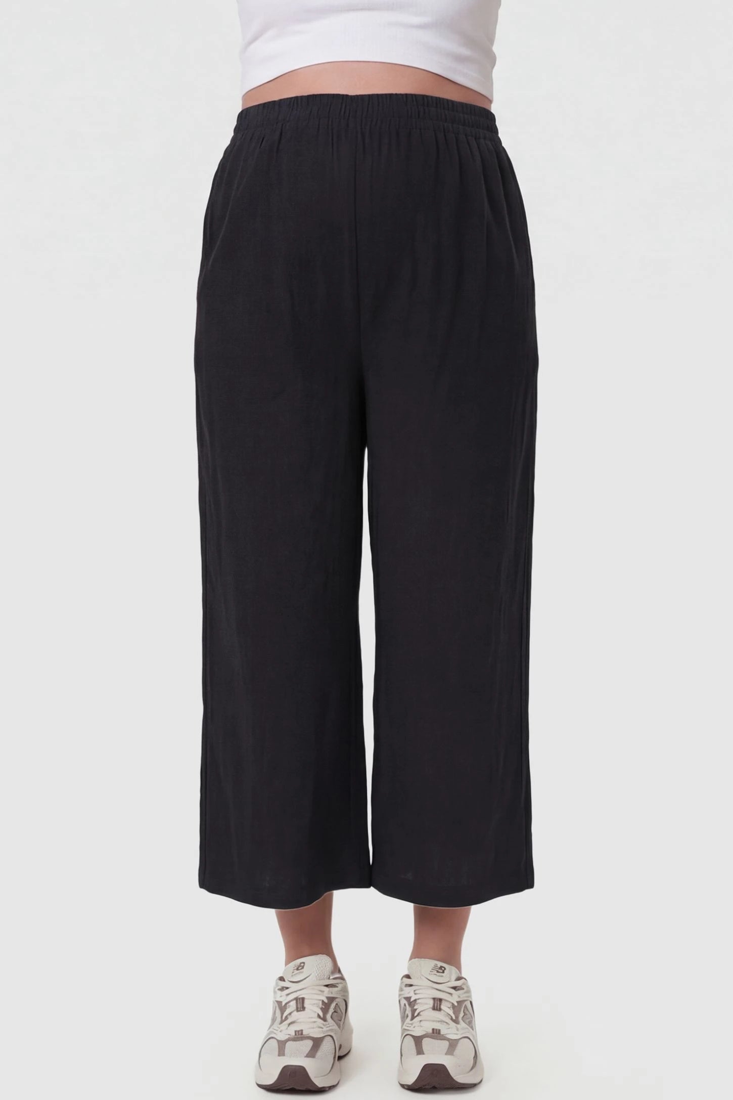 Elastic High Waisted Cropped Maternity Pants in Black featuring a flexible waistband on a pregnant model, front view.