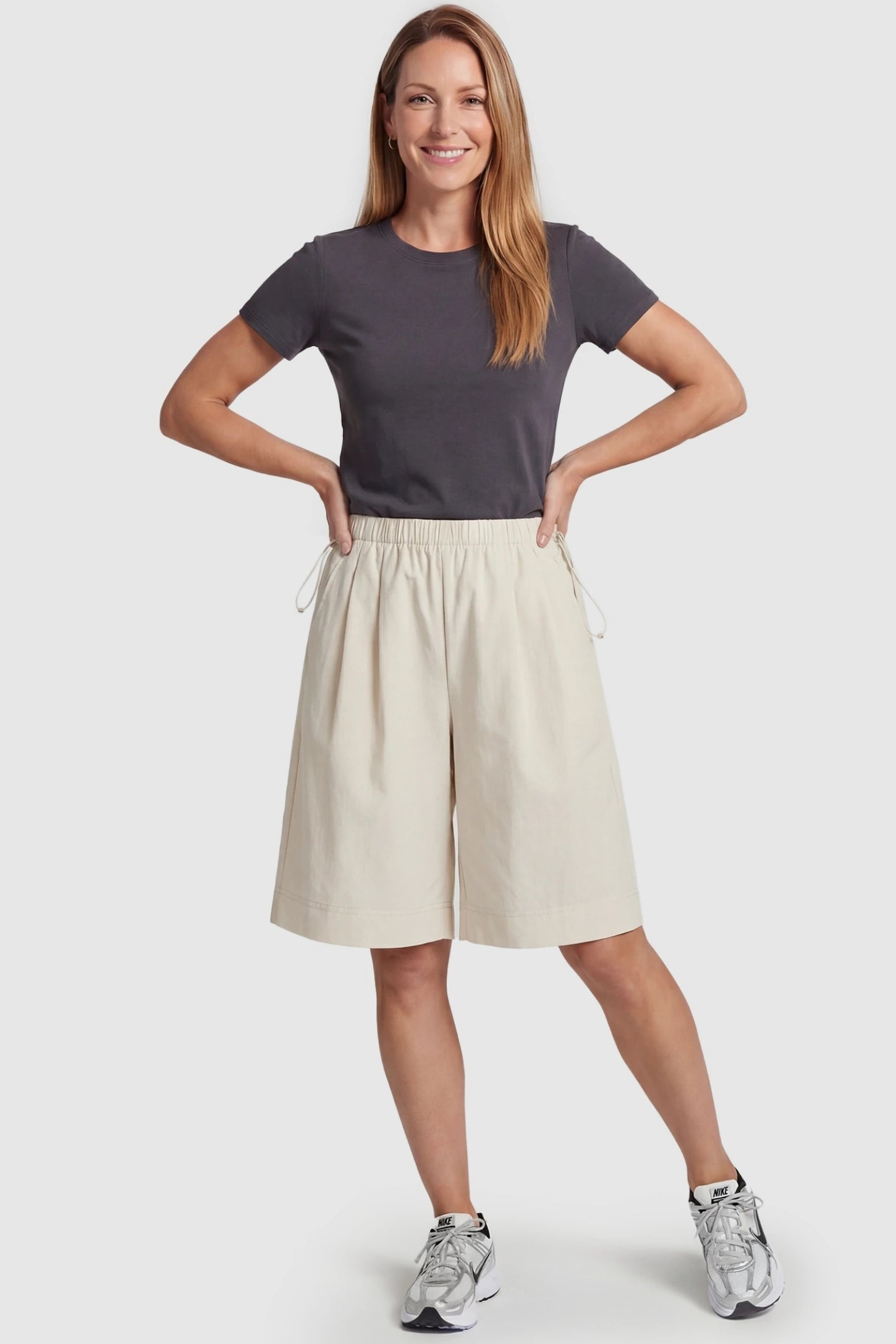 Pocketed Side Drawstring Maternity Shorts Beige Elasticated Waist Maternity Lounge Shorts featuring a flowy wide-leg cut on a postpartum model, front view.