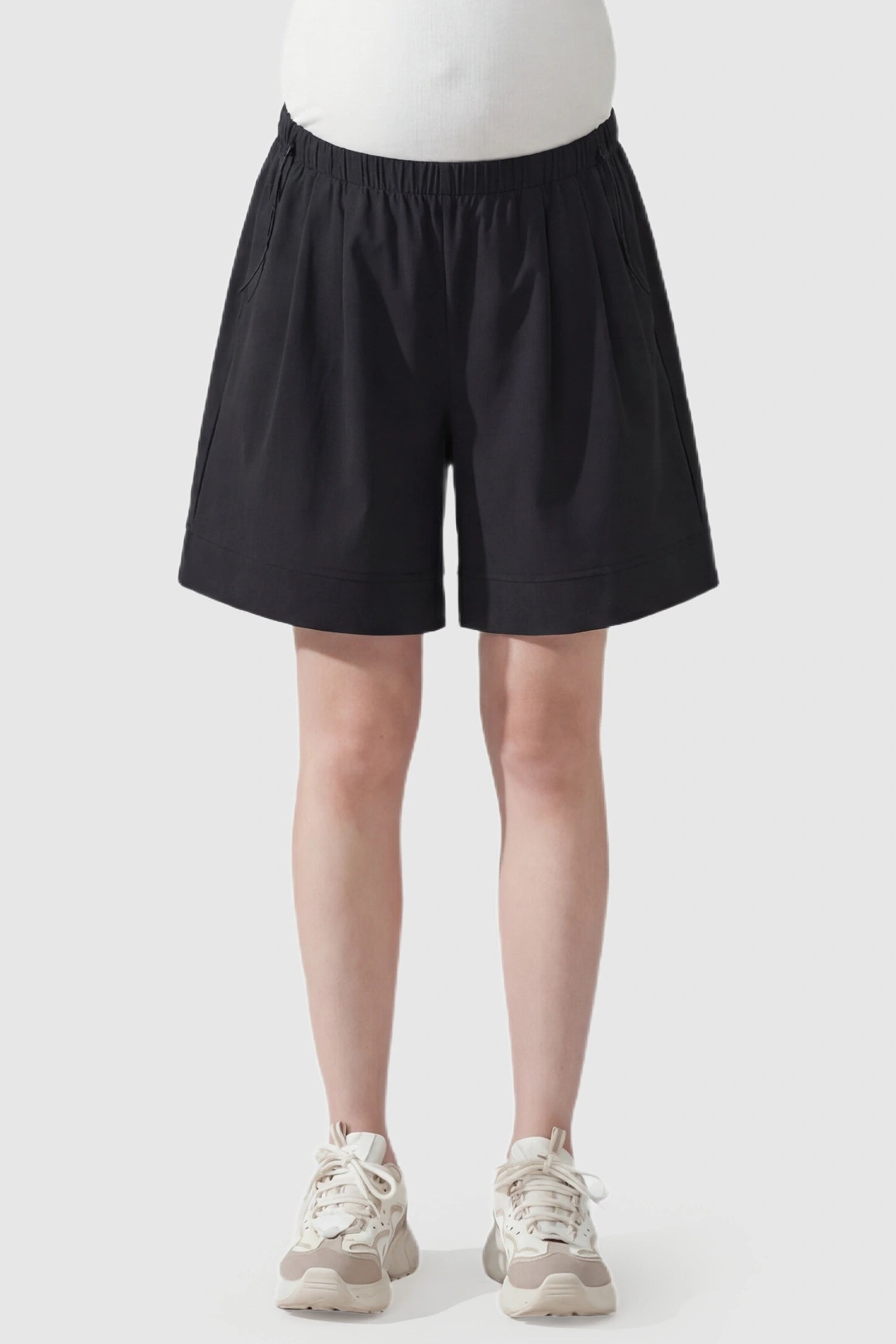 Pocketed Side Drawstring Maternity Shorts Black Elasticated Waist Soft Wide Leg Maternity Shorts featuring a supportive gathered waistband on a pregnant model, front view.
