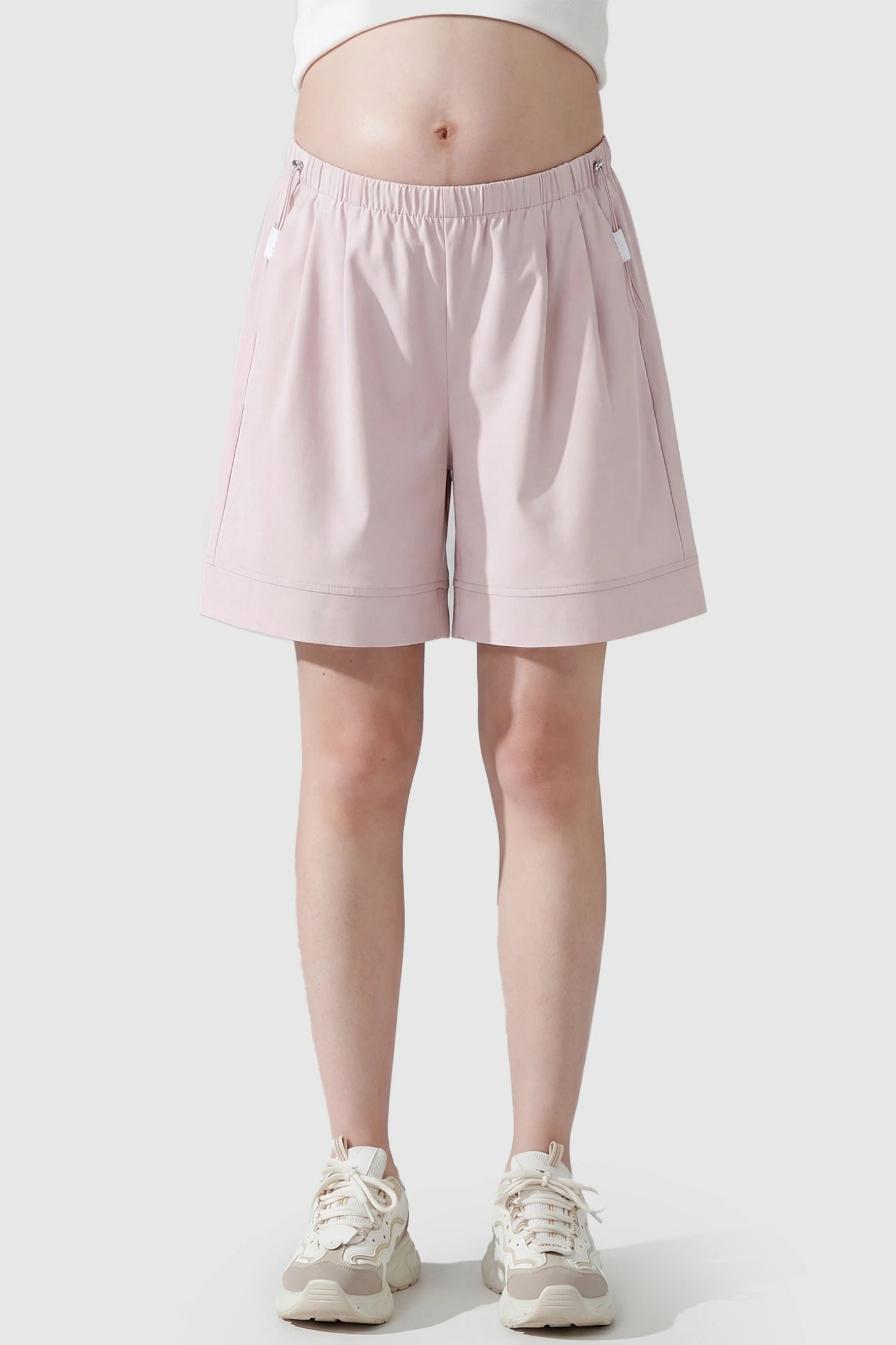 Pocketed Side Drawstring Maternity Shorts Front view of Light Pink Elasticated Waist Maternity Shorts featuring soft-touch fabric on a pregnant model.