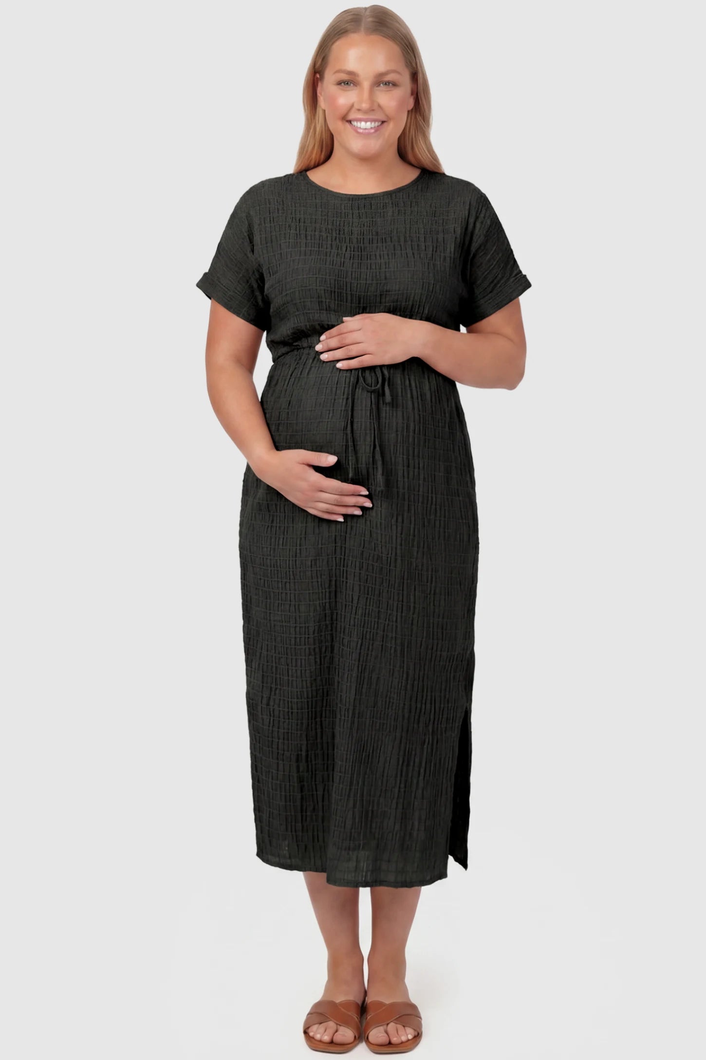 Empire Waist Round Neck Maternity Midi Dress Empire Waist Round Neck Maternity Midi Dress in Black featuring elasticated waistband with a decorative tie detail on a plus size pregnant model, front view.