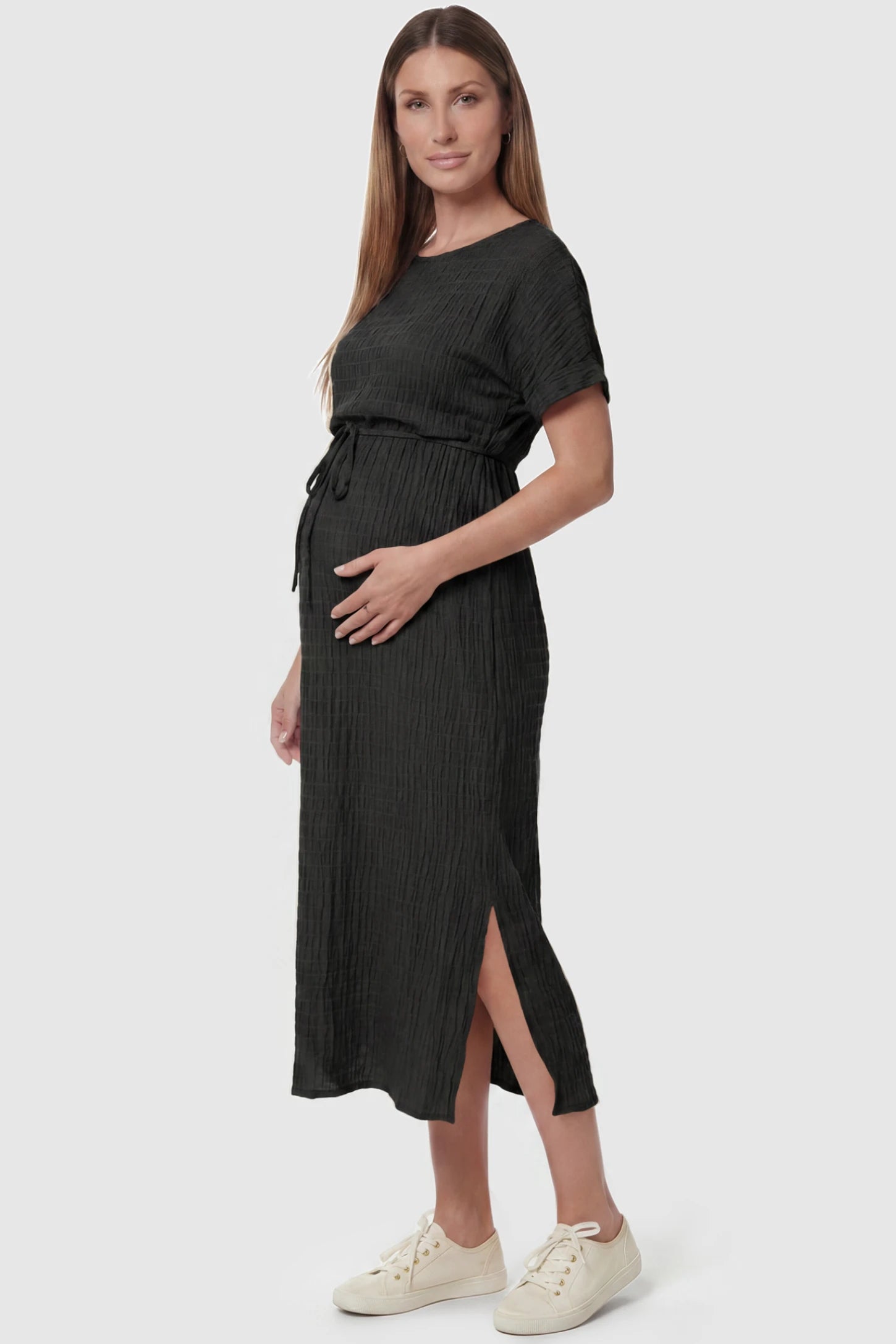 Empire Waist Round Neck Maternity Midi Dress Empire Waist Round Neck Maternity Midi Dress in Black featuring elasticated waistband with a decorative tie detail on a pregnant model, side view.