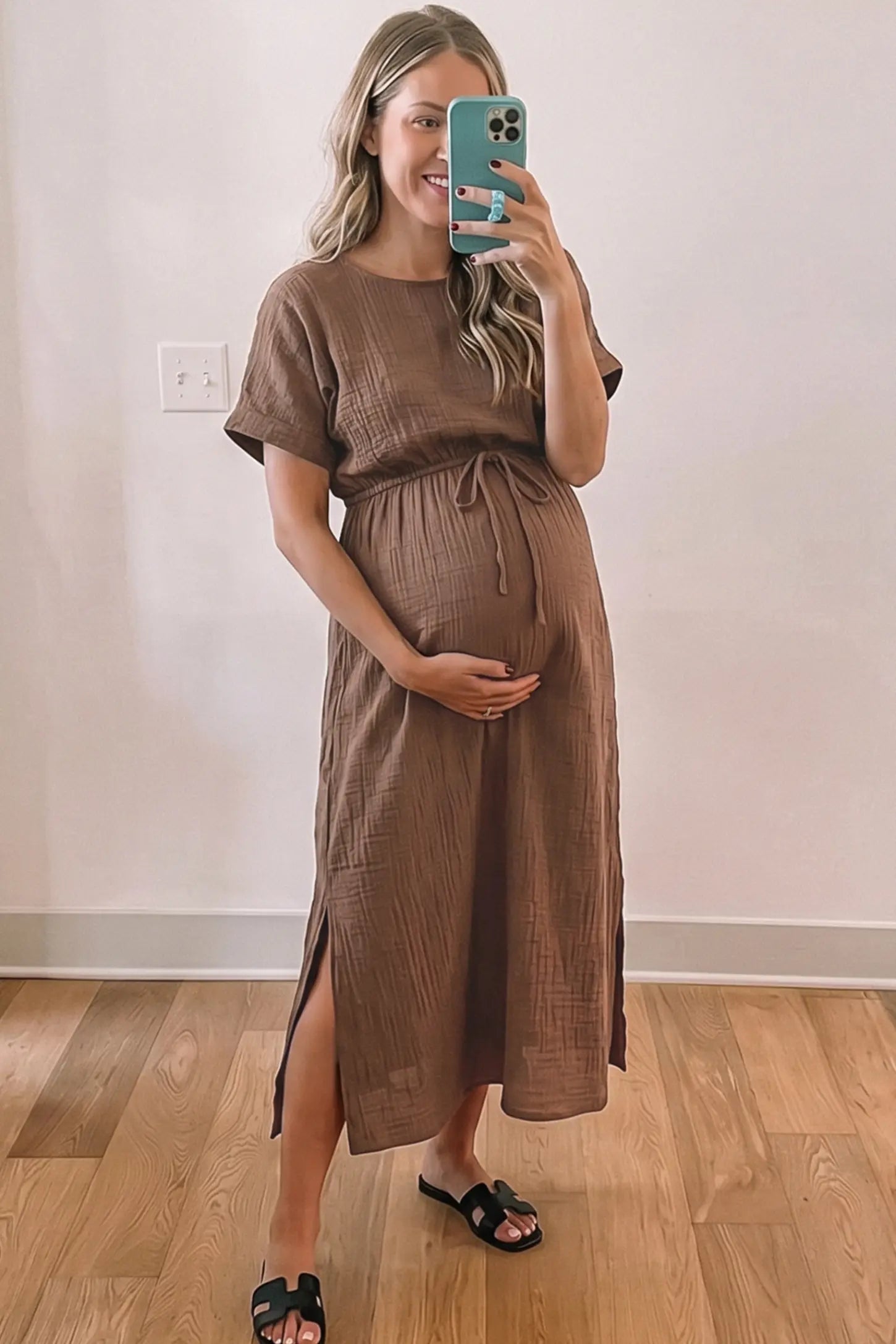 Empire Waist Round Neck Maternity Midi Dress Empire Waist Round Neck Maternity Midi Dress in Brown featuring elasticated waistband with a decorative tie detail on a plus size pregnant woman in indoor setting, front view.
