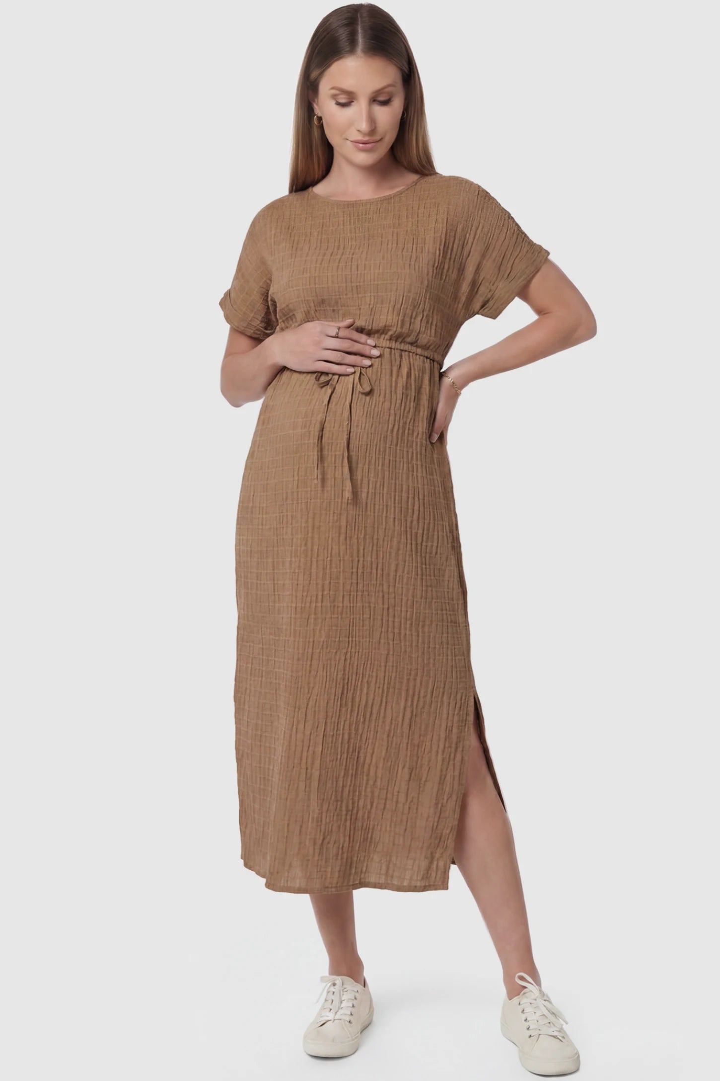 Empire Waist Round Neck Maternity Midi Dress Empire Waist Round Neck Maternity Midi Dress in Brown featuring elasticated waistband with a decorative tie detail on a pregnant model, front view.
