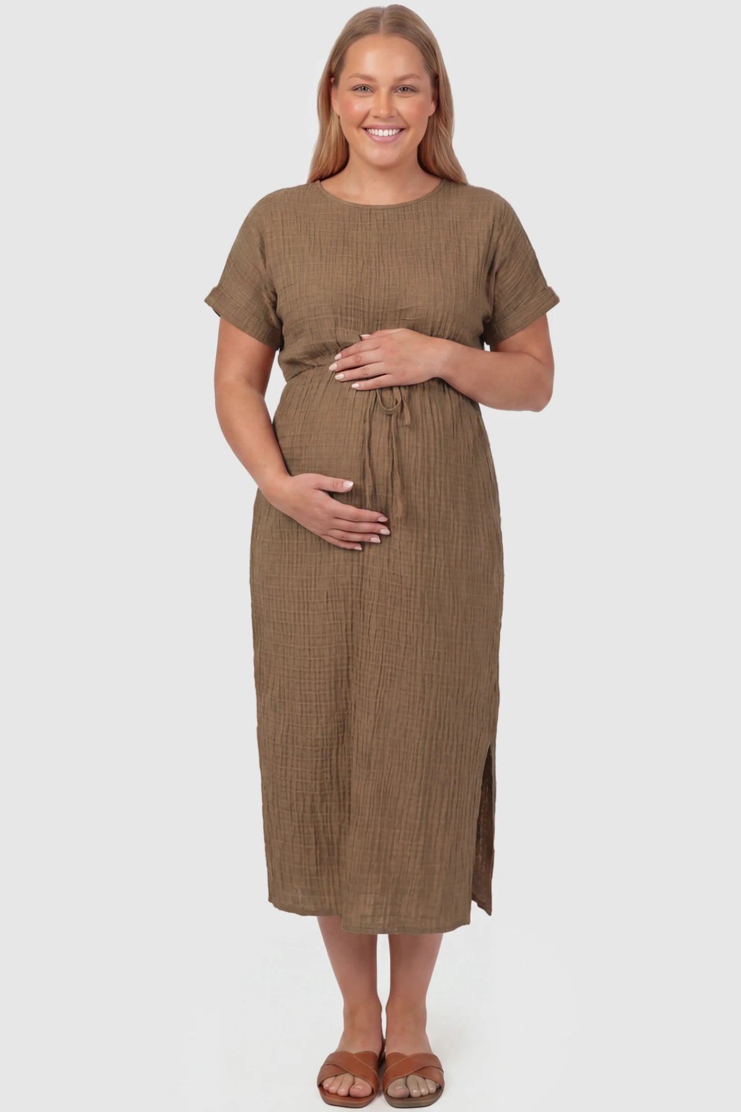 Empire Waist Round Neck Maternity Midi Dress Empire Waist Round Neck Maternity Midi Dress in Brown featuring elasticated waistband with a decorative tie detail on a plus size pregnant model, front view.