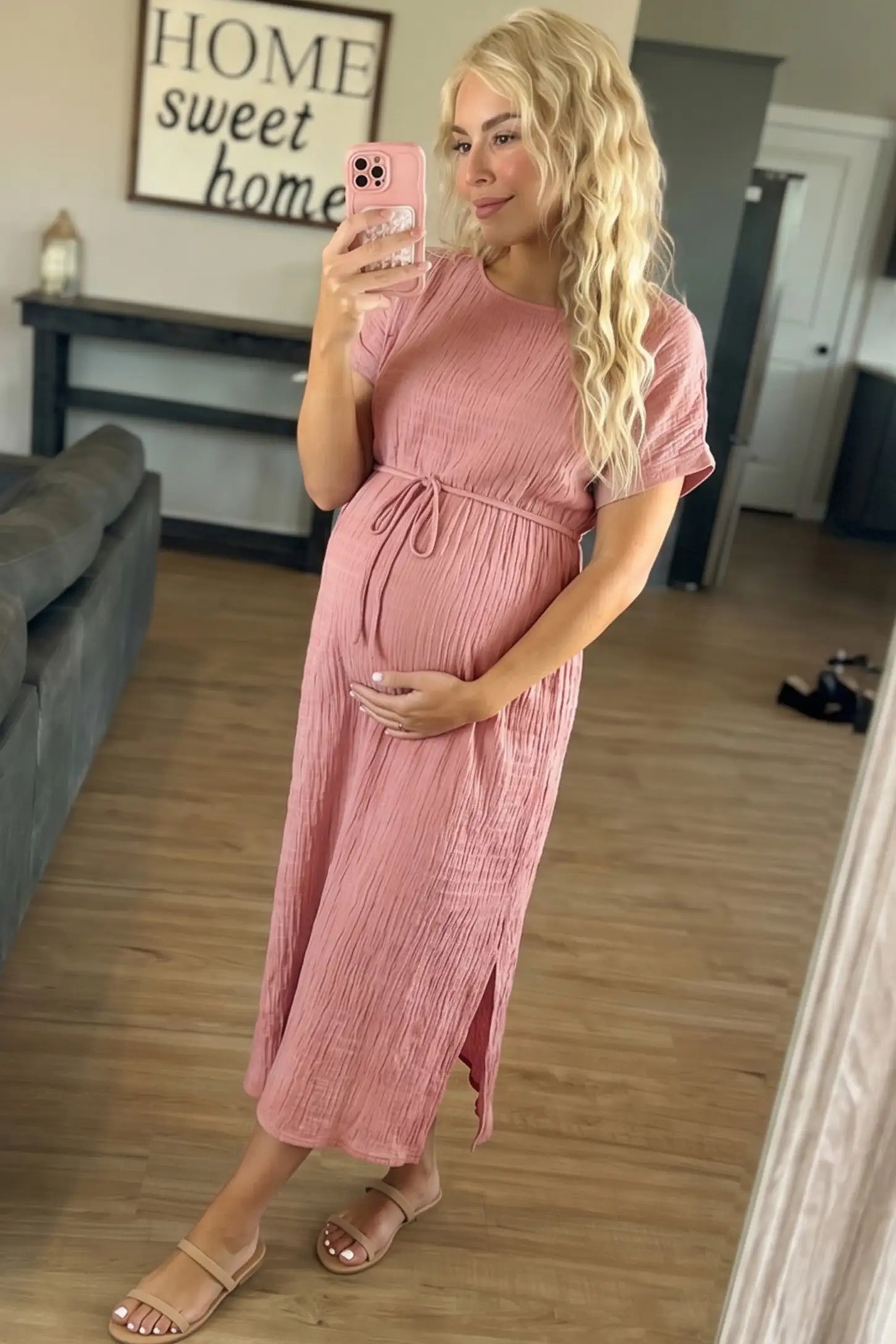 Empire Waist Round Neck Maternity Midi Dress Empire Waist Round Neck Maternity Midi Dress in Pink featuring elasticated waistband with a decorative tie detail on a plus size pregnant woman in indoor setting, front view.