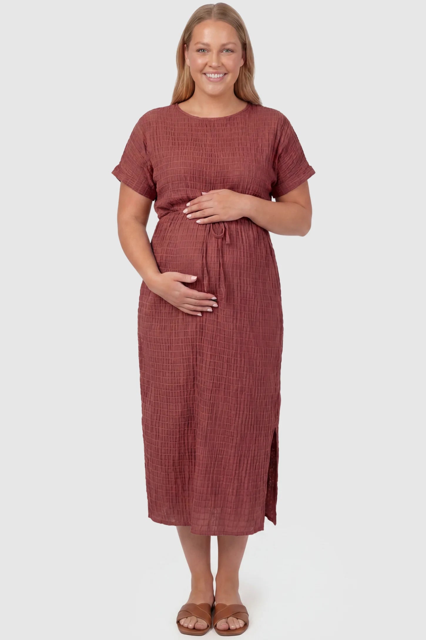 Empire Waist Round Neck Maternity Midi Dress Empire Waist Round Neck Maternity Midi Dress in Wine Red featuring elasticated waistband with a decorative tie detail on a plus size pregnant model, front view.