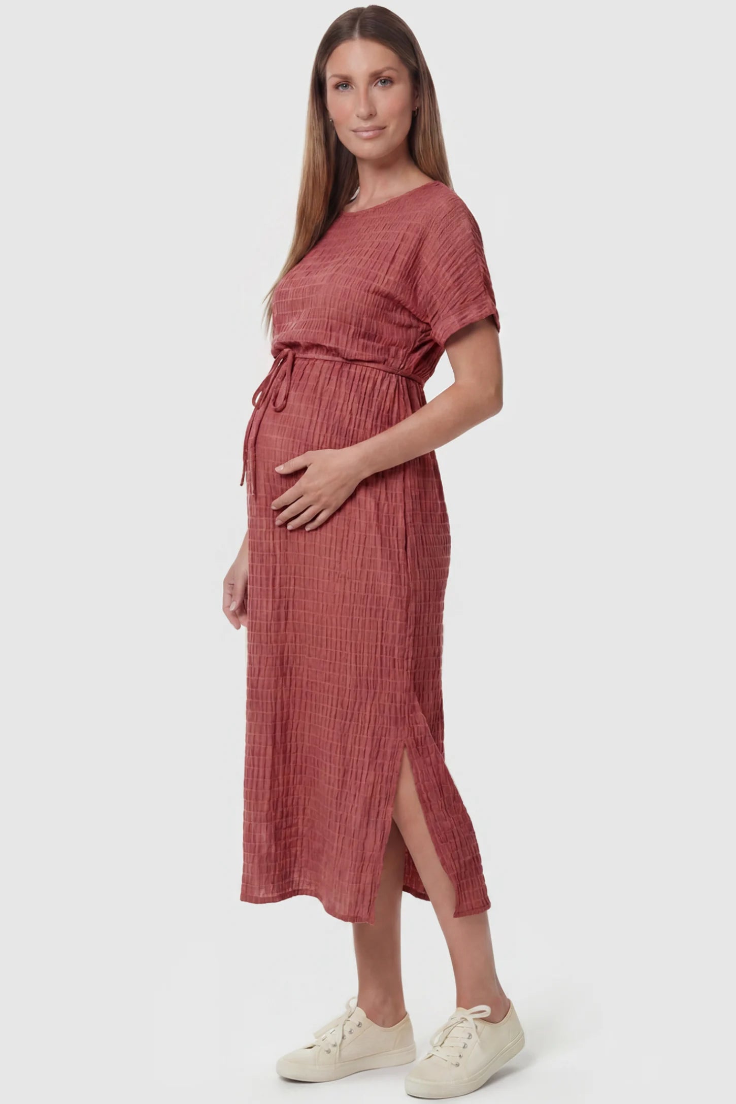 Empire Waist Round Neck Maternity Midi Dress Empire Waist Round Neck Maternity Midi Dress in Wine Red featuring elasticated waistband with a decorative tie detail on a pregnant model, side view.