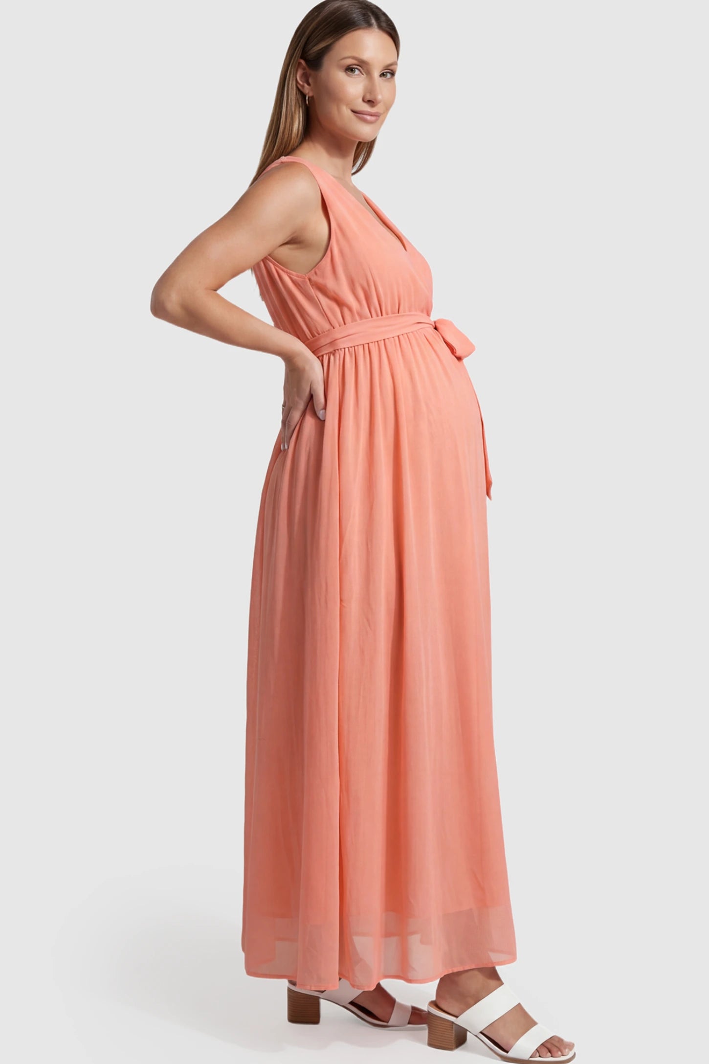 Empire Waist Tie-Front Sleeveless Maternity Maxi Dress Empire Waist Tie-Front Sleeveless Maternity Maxi Dress in Pink featuring a tie front and empire waist on a pregnant model showing side.