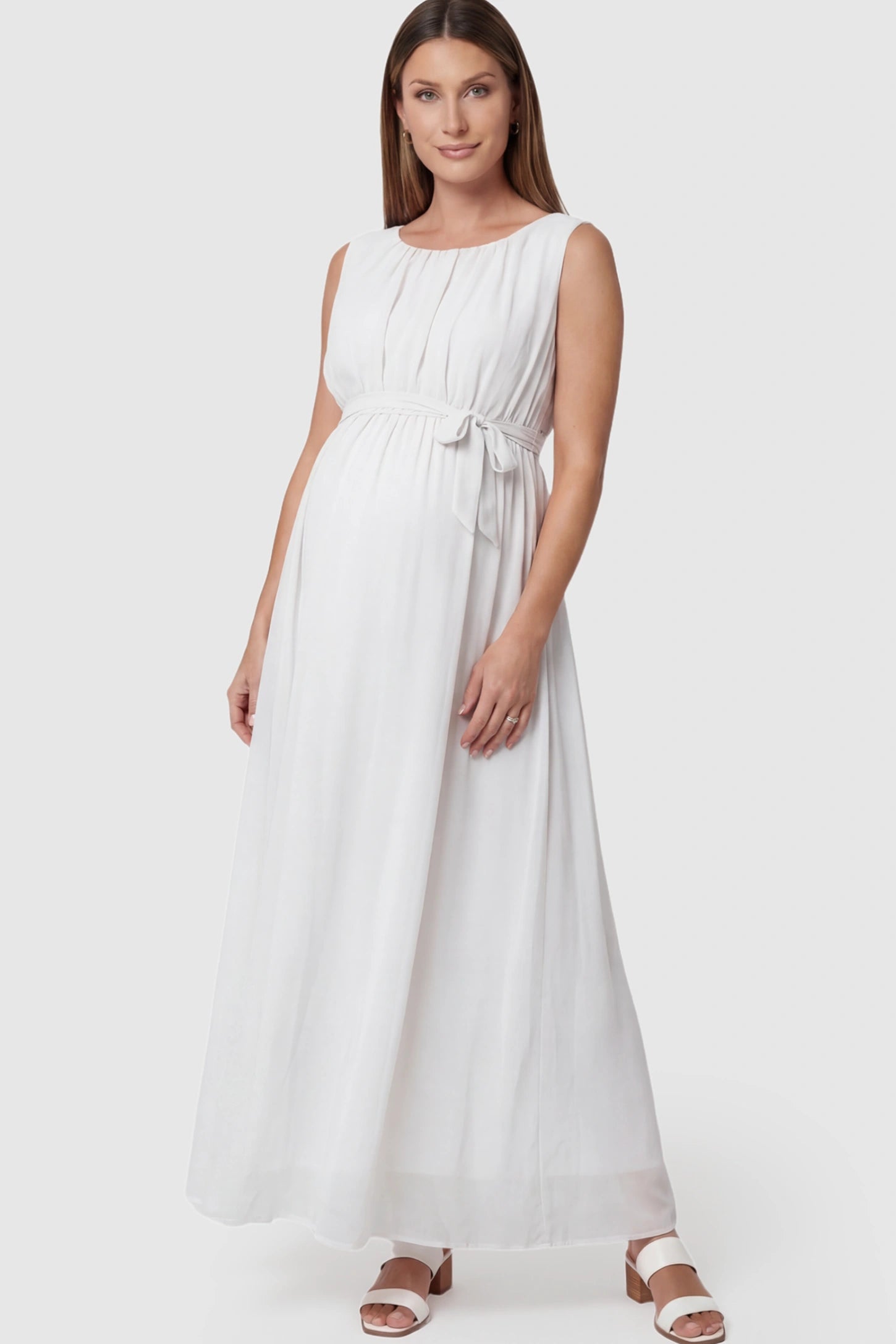 Empire Waist Tie-Front Sleeveless Maternity Maxi Dress Empire Waist Tie-Front Sleeveless Maternity Maxi Dress in White featuring a tie front and empire waist on a pregnant model posing front.