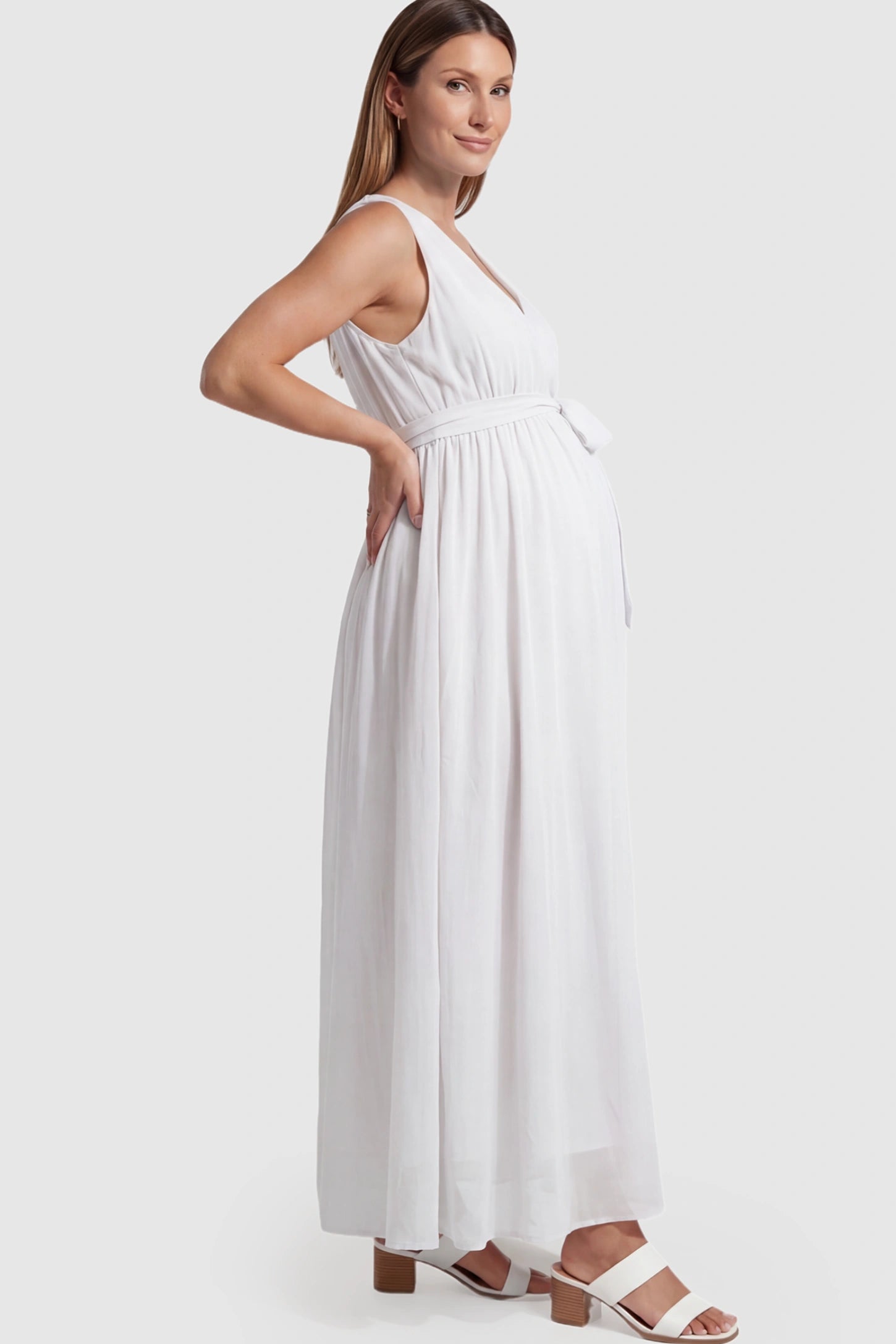 Empire Waist Tie-Front Sleeveless Maternity Maxi Dress Empire Waist Tie-Front Sleeveless Maternity Maxi Dress in White featuring a tie front and empire waist on a pregnant model showing side.
