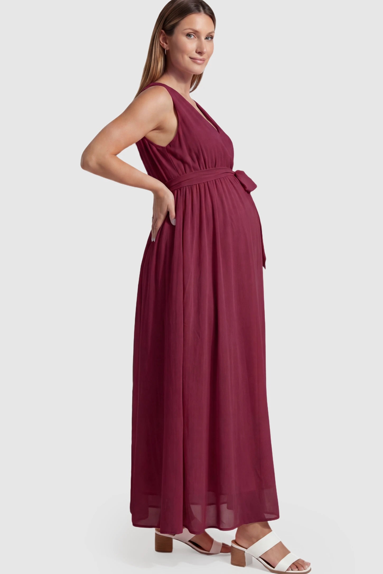 Empire Waist Tie-Front Sleeveless Maternity Maxi Dress Empire Waist Tie-Front Sleeveless Maternity Maxi Dress in Wine Red featuring a tie front and empire waist on a pregnant model showing side.