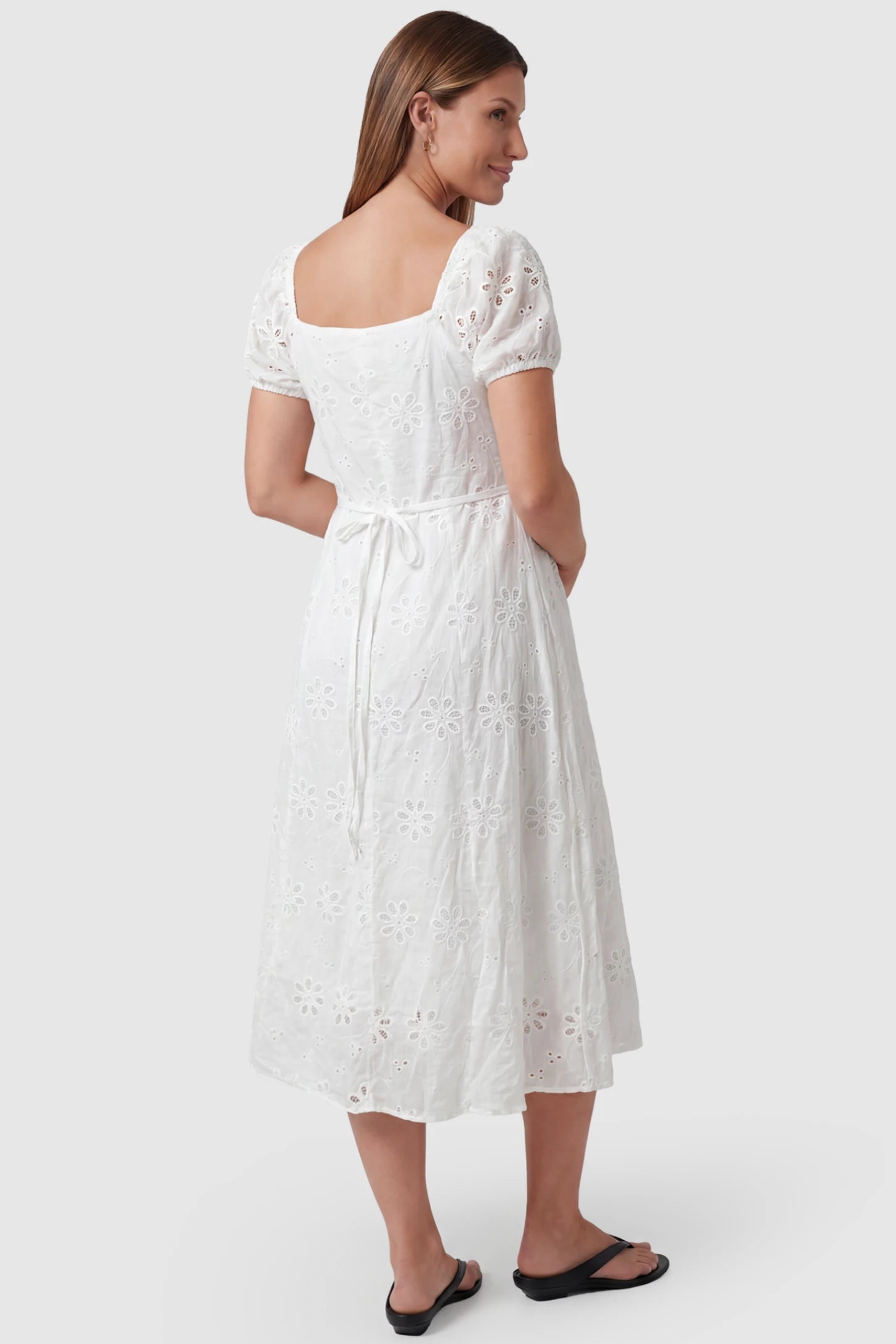 Eyelet Embroidered Short Sleeve Maternity Midi Dress Eyelet Embroidered Short Sleeve Maternity Midi Dress in white featuring a tie-back and A-line silhouette on a pregnant model, back view.