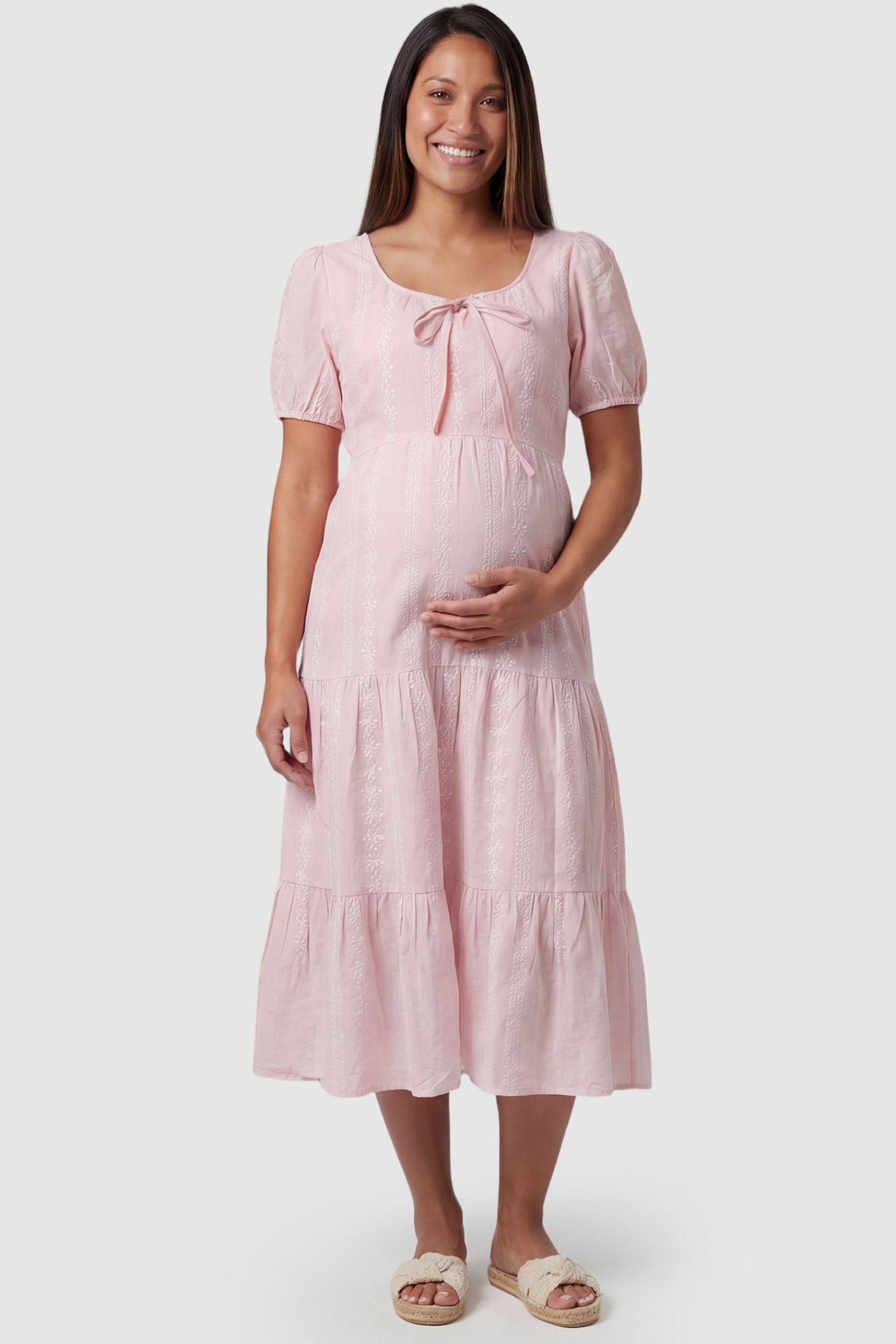 Eyelet Scoop Neck Tiered Maternity Dress Eyelet Scoop Neck Tiered Maternity Dress in Pink featuring a front tie detail on a pregnant model, front view.