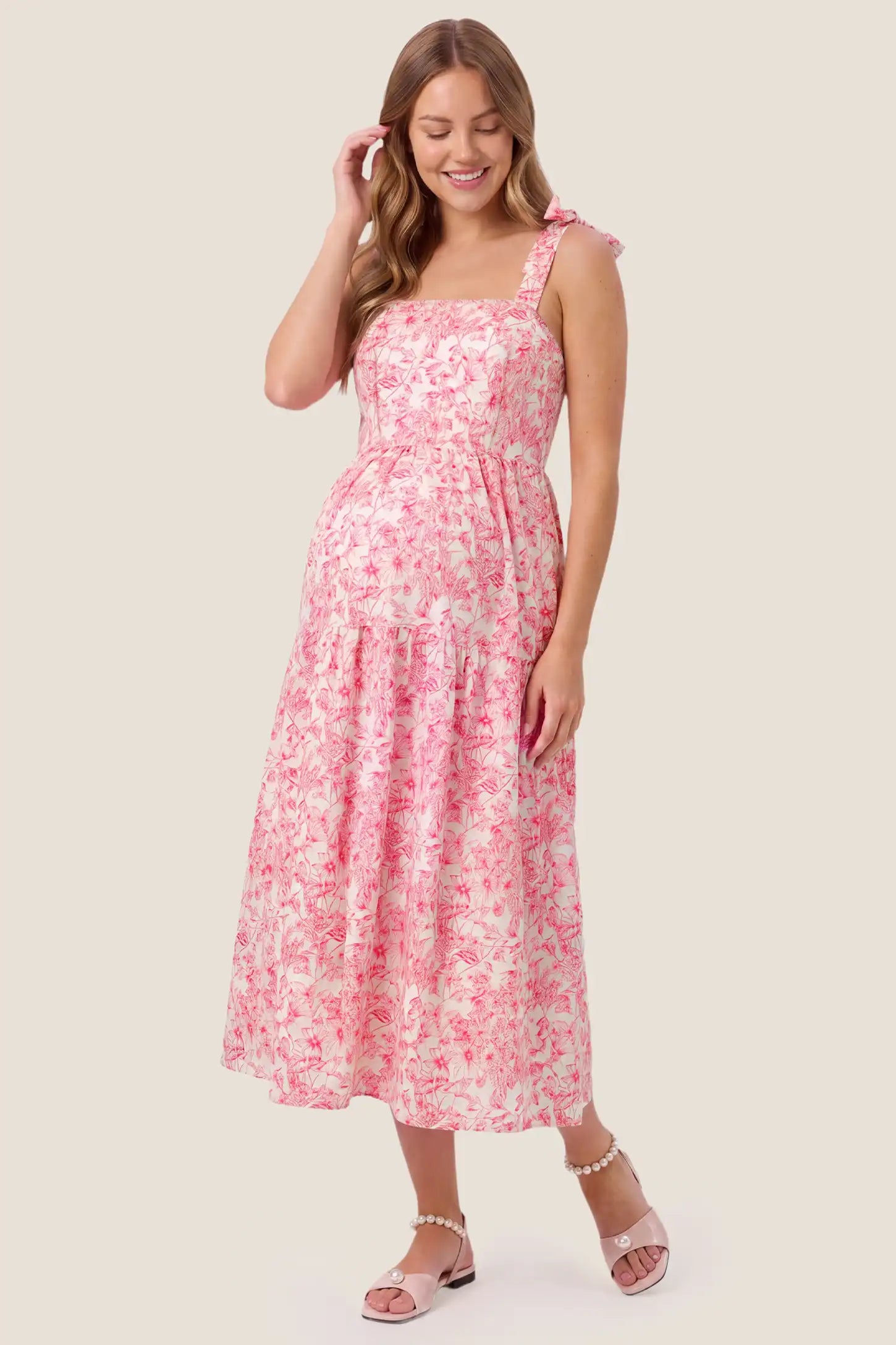 Floral Cami Tiered Maxi Maternity Dress Floral Cami Tiered Maxi Maternity Dress in pink floral showcasing delicate spaghetti straps and a multi-tiered skirt, front view on a pregnant model.
