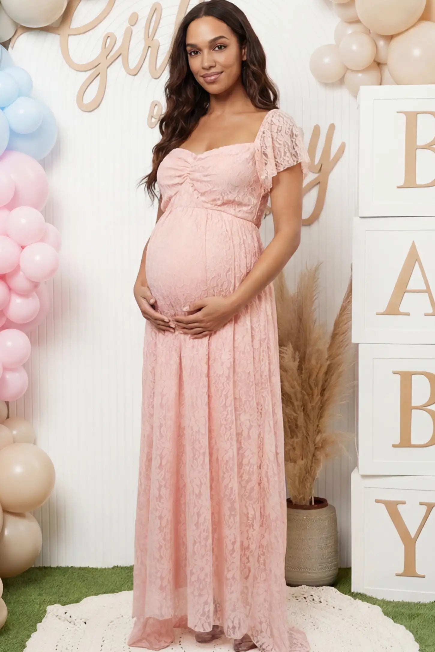Floral Lace Flutter Sleeve Maternity Maxi Dress Floral Lace Flutter Sleeve Maternity Maxi Dress in Pink featuring sweetheart neckline on a pregnant woman showing front.