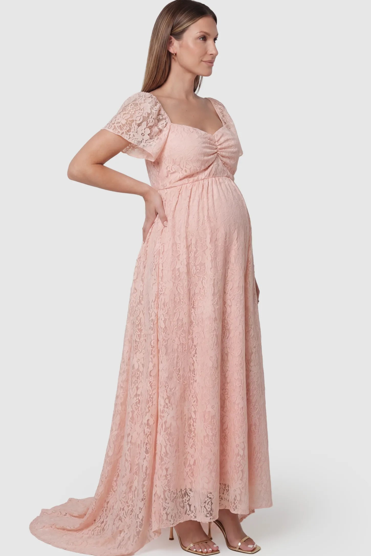 Floral Lace Flutter Sleeve Maternity Maxi Dress Floral Lace Flutter Sleeve Maternity Maxi Dress in Pink featuring sweetheart neckline on a pregnant model showing side.