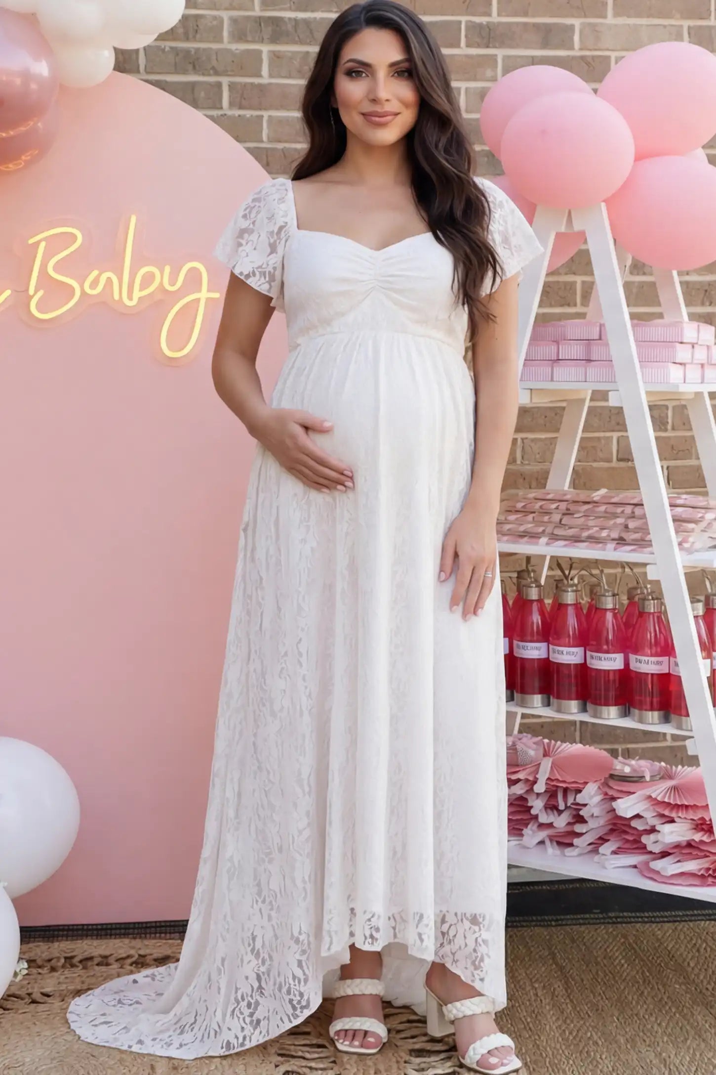 Floral Lace Flutter Sleeve Maternity Maxi Dress Floral Lace Flutter Sleeve Maternity Maxi Dress in White featuring sweetheart neckline on a pregnant woman showing front.