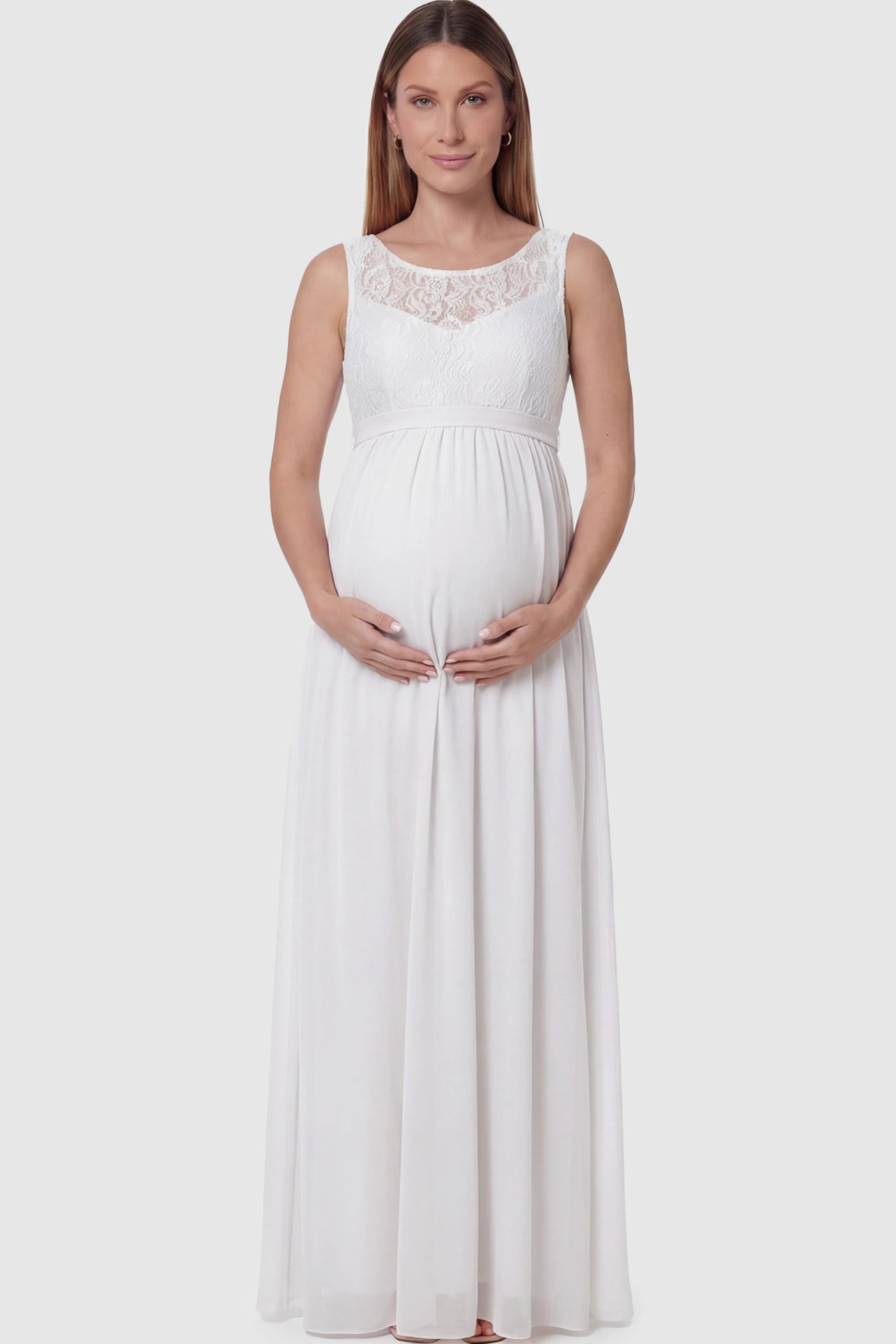 Floral Lace Sleeveless Maternity Maxi Dress Floral Lace Sleeveless Maternity Maxi Dress in White featuring a flowing skirt on a pregnant model posing front.