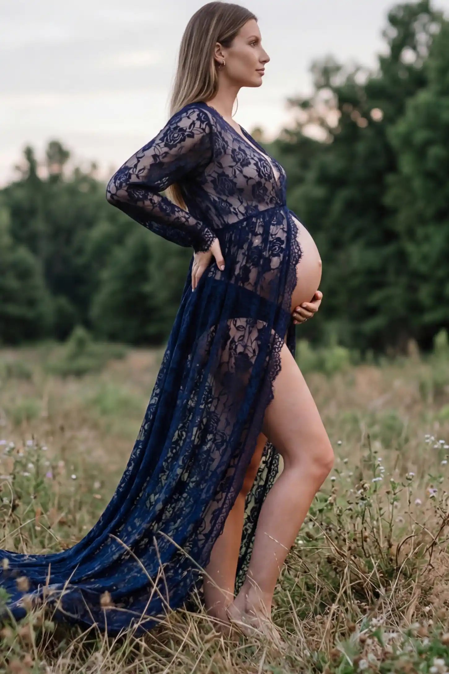 Floral Lace V-Neck Long Sleeve Maternity Photoshoot Gown Floral Lace V-Neck Long Sleeve Maternity Photoshoot Gown in Navy Blue featuring long sleeves and high front slit on a pregnant model showing side.